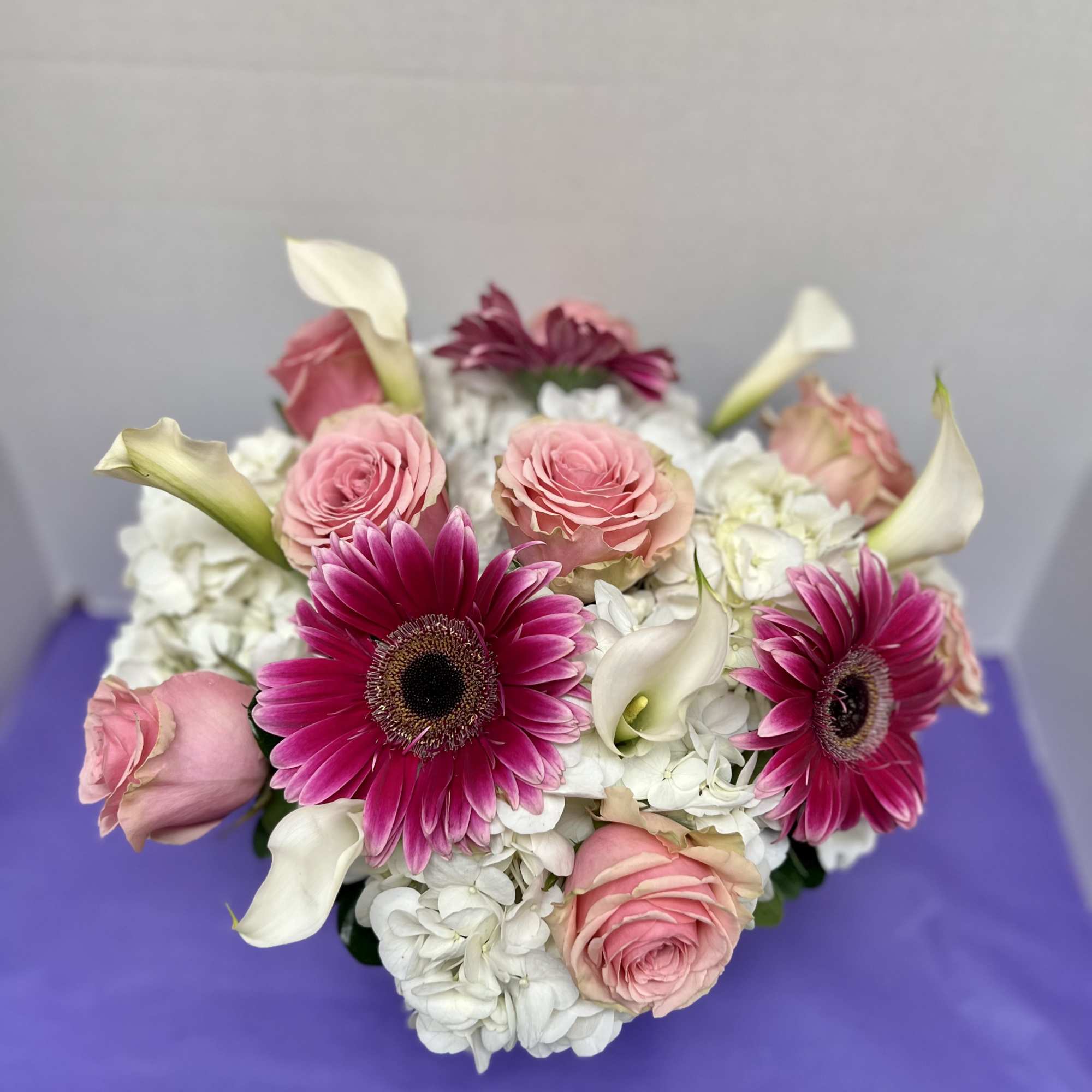 Pink roses and magenta gerbera daisies with white calla lilies and hydrangeas