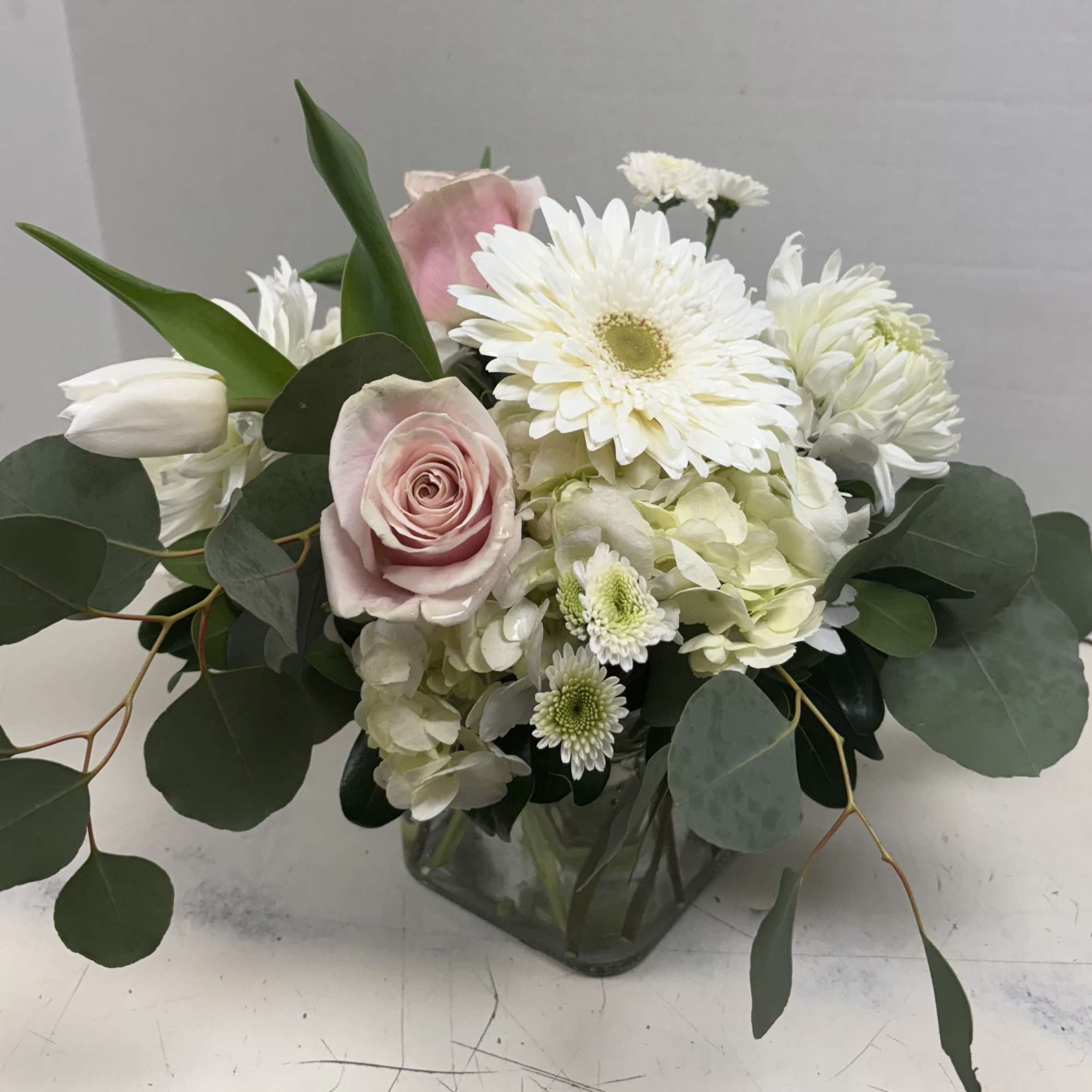 Pink roses and white flowers arranged in a clear glass vase