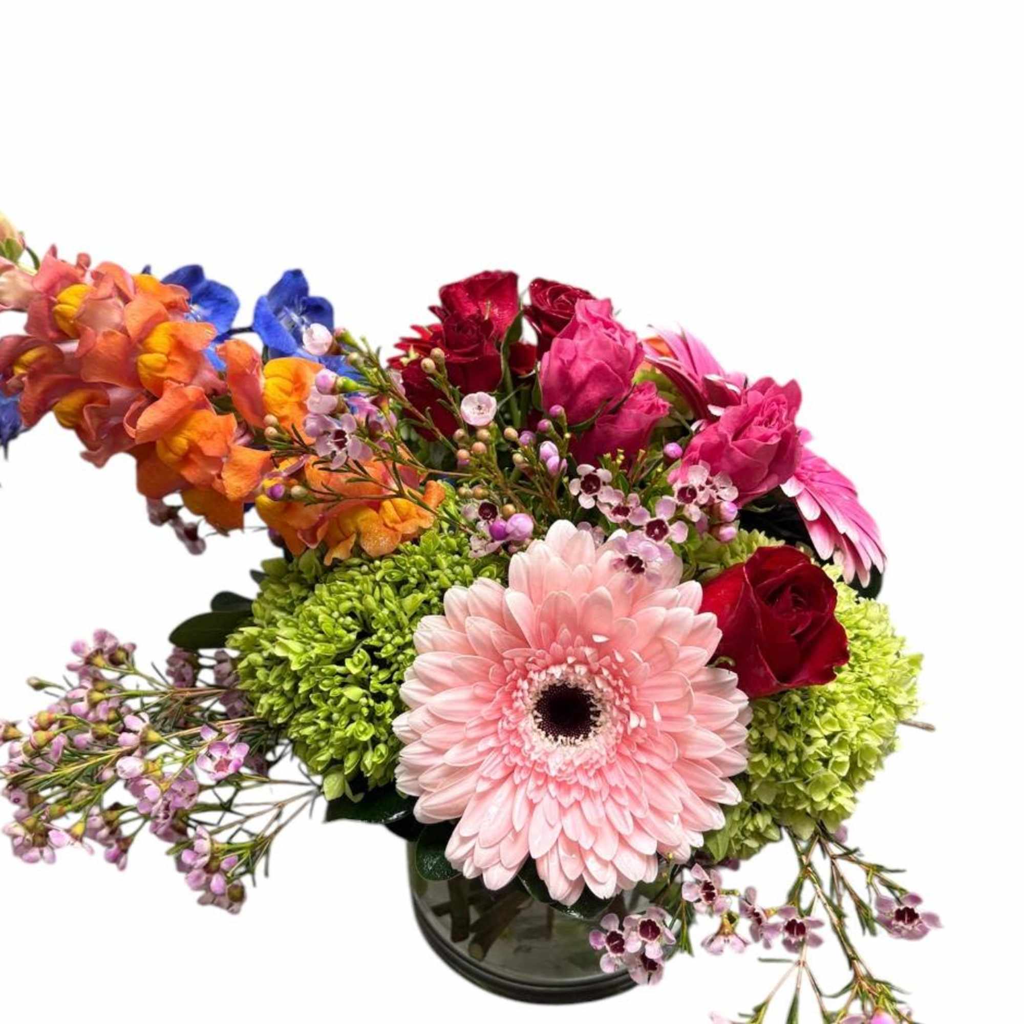 Colorful mixed flower arrangement in a glass vase with a pink gerbera daisy and roses