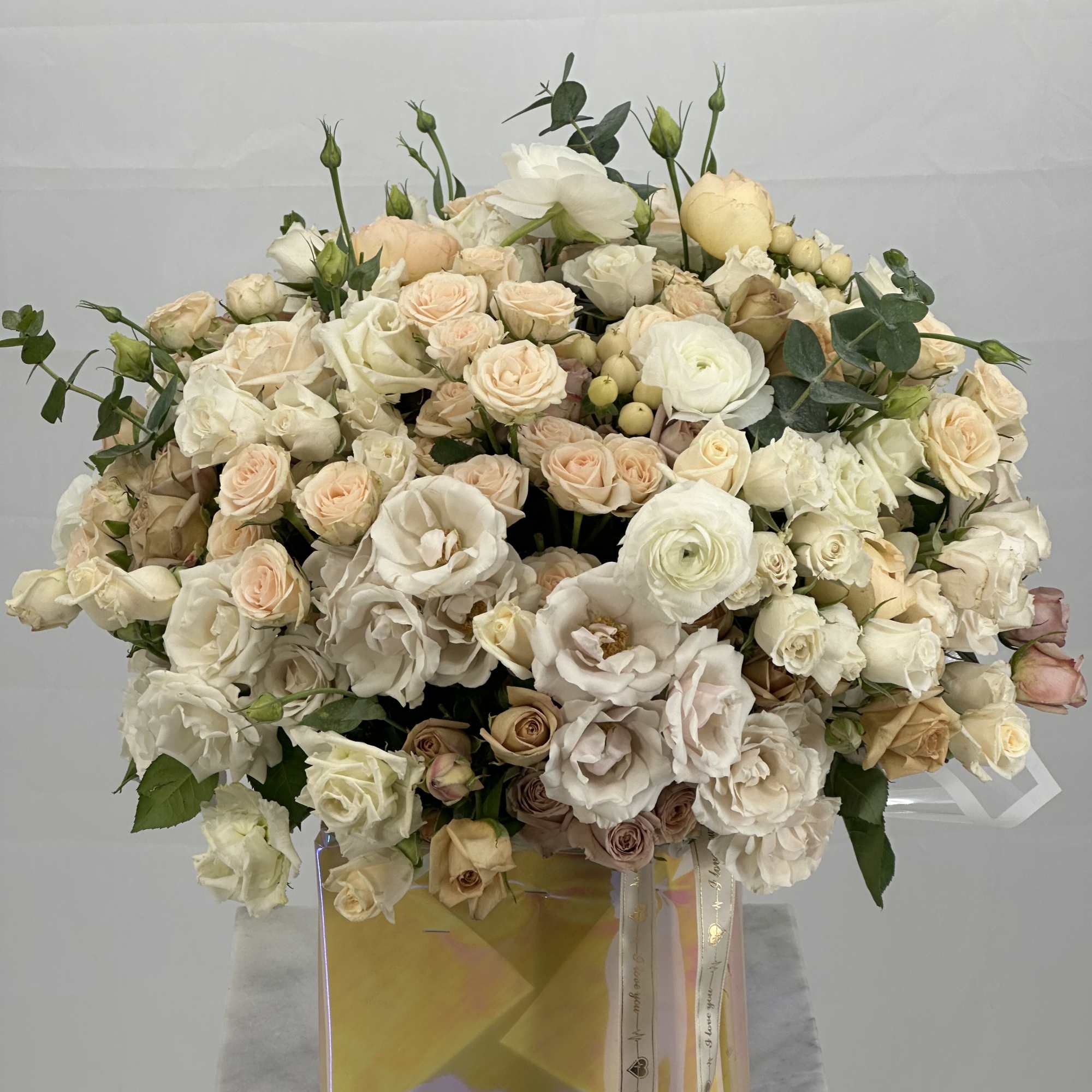 Large cream and blush rose arrangement in a square iridescent box