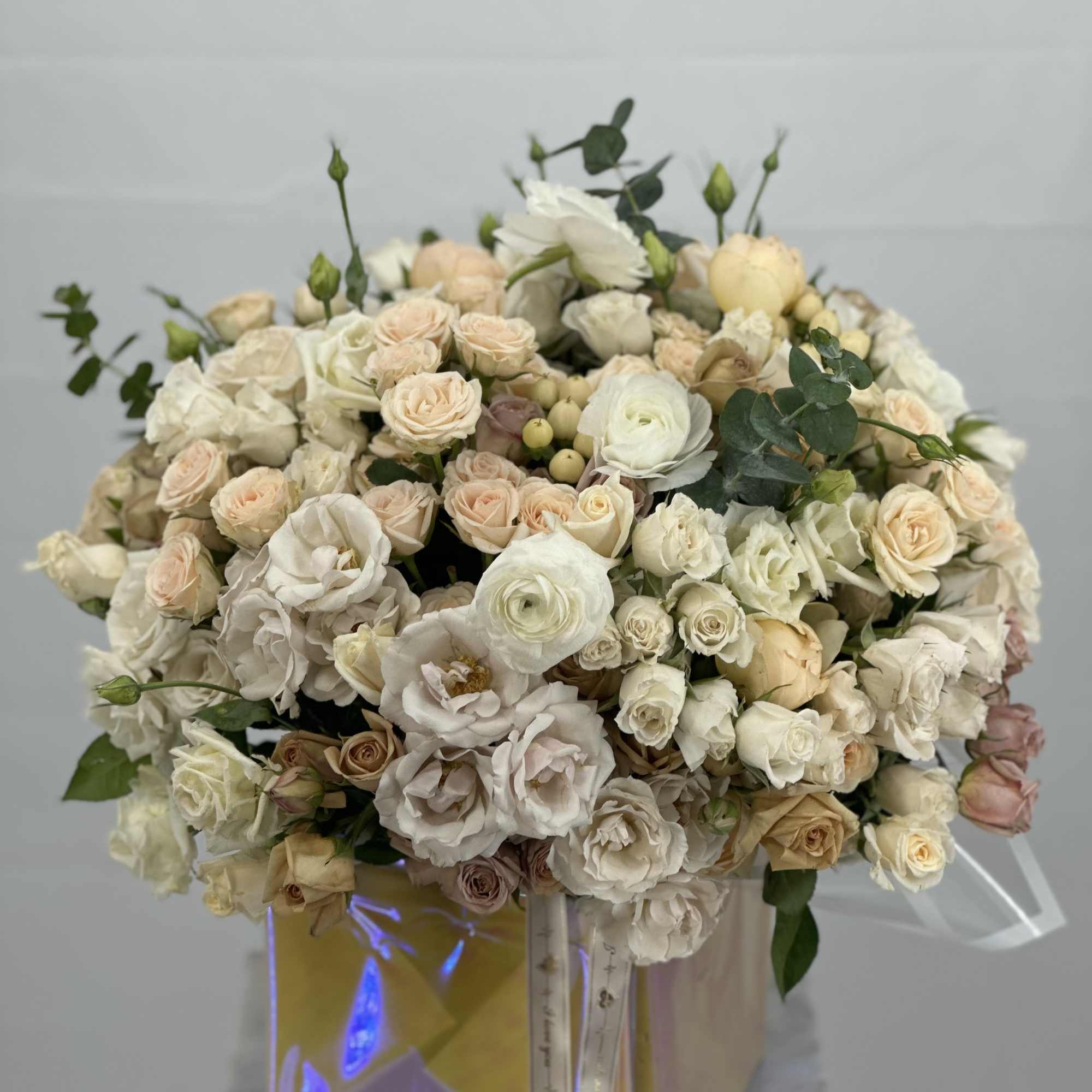 Large bouquet of cream and blush roses with white blooms in a gift box