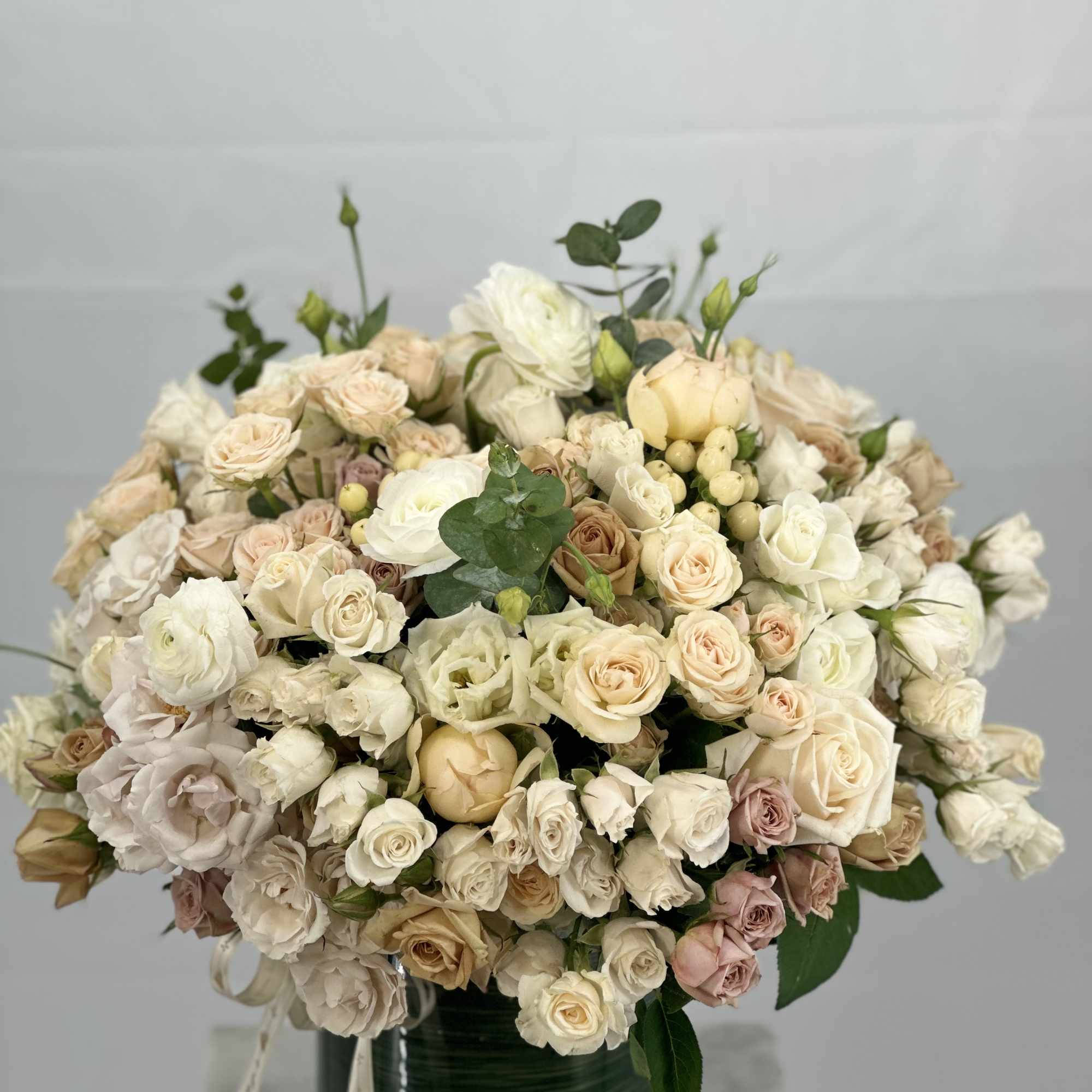 Cream and blush rose bouquet in a dark green vase