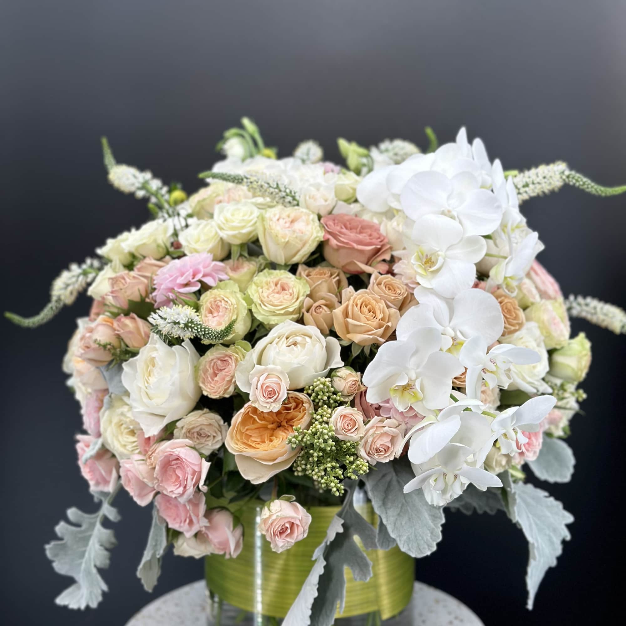 Pastel rose bouquet with white orchids in a glass vase