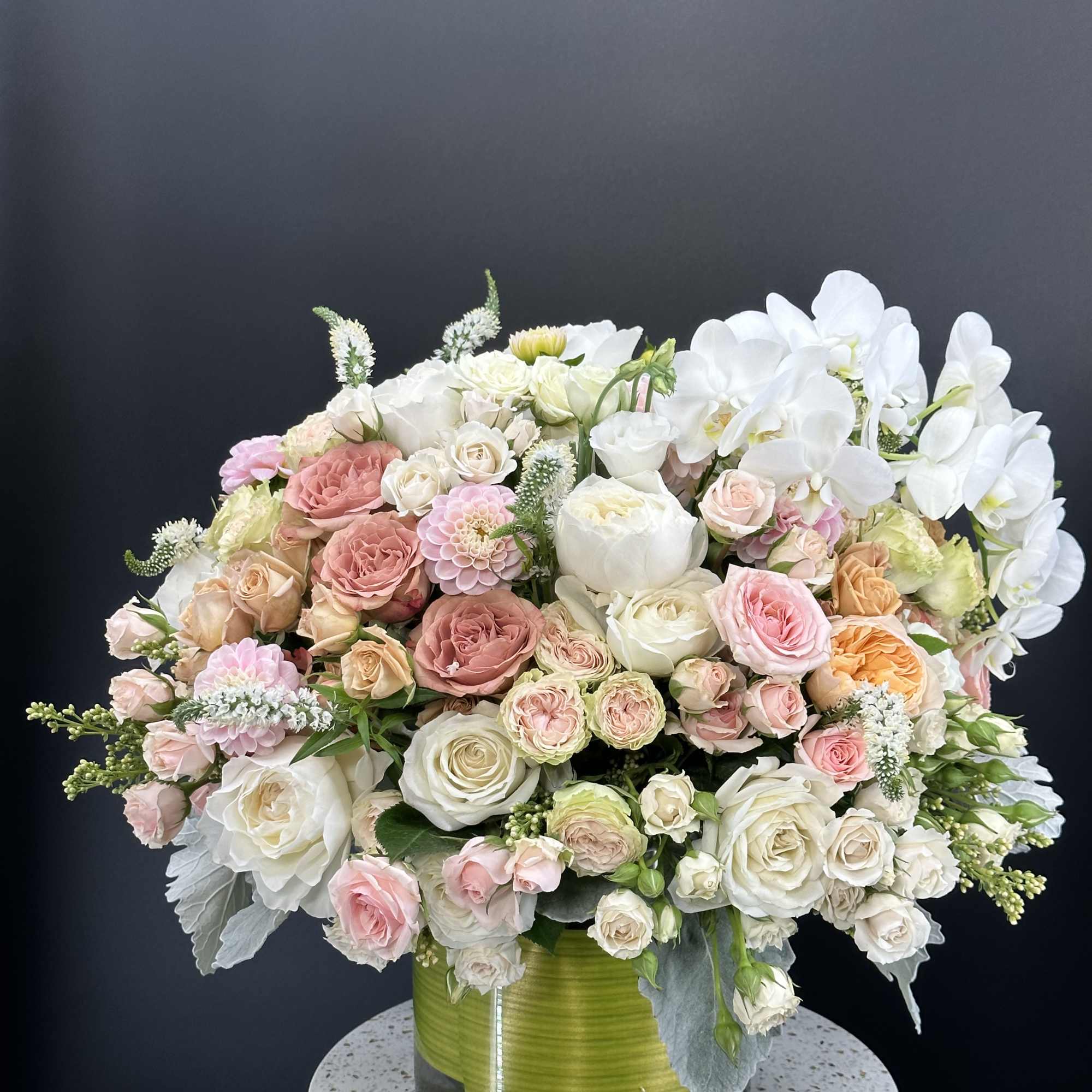 Large bouquet of white and blush roses with white orchids in a glass vase