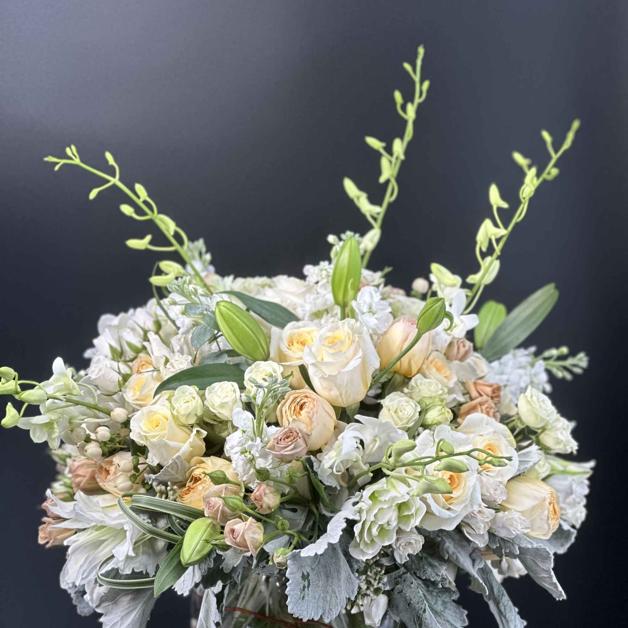 Cream and peach bouquet in a glass vase with tall green stems