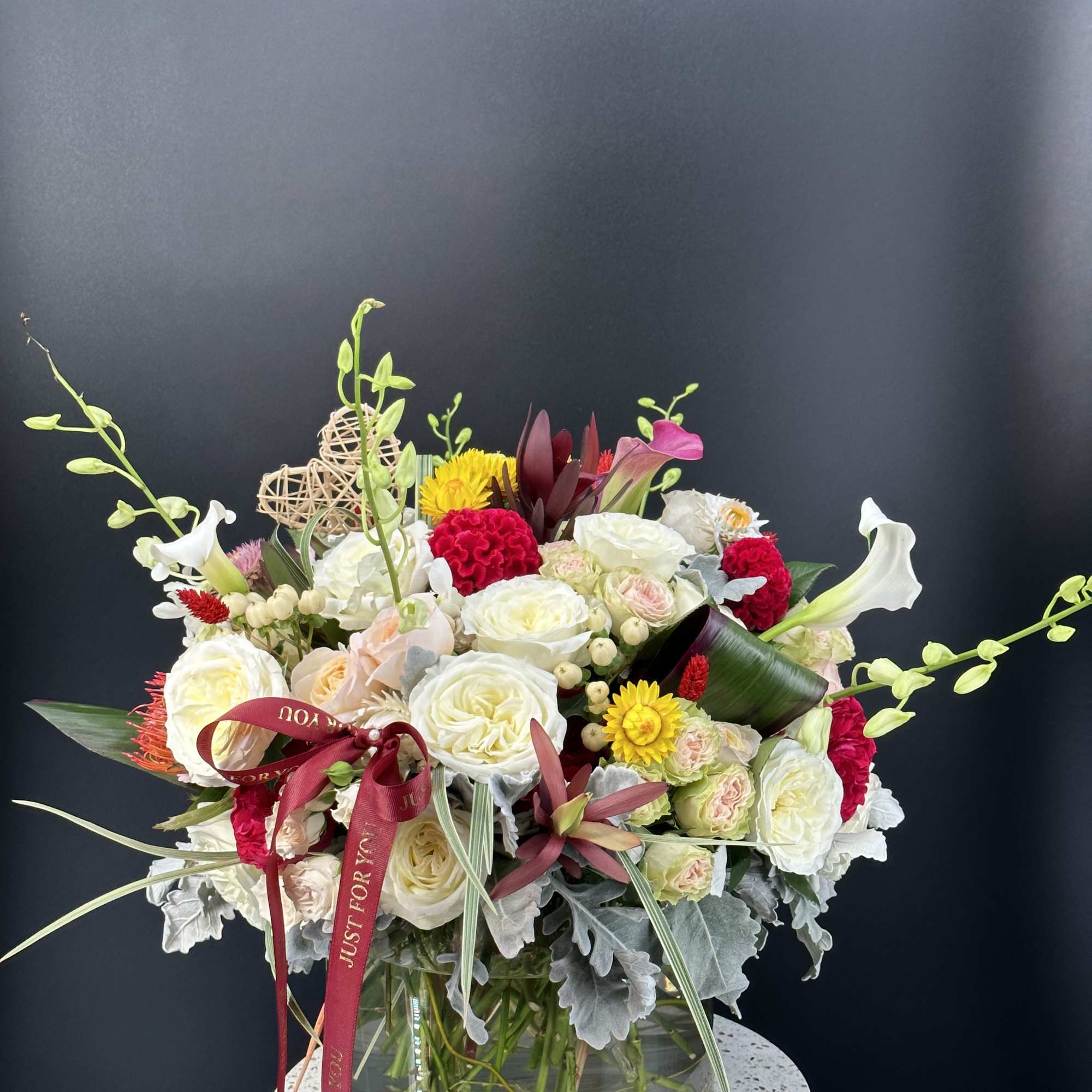 Mixed bouquet of white, pink, and yellow flowers in a glass vase