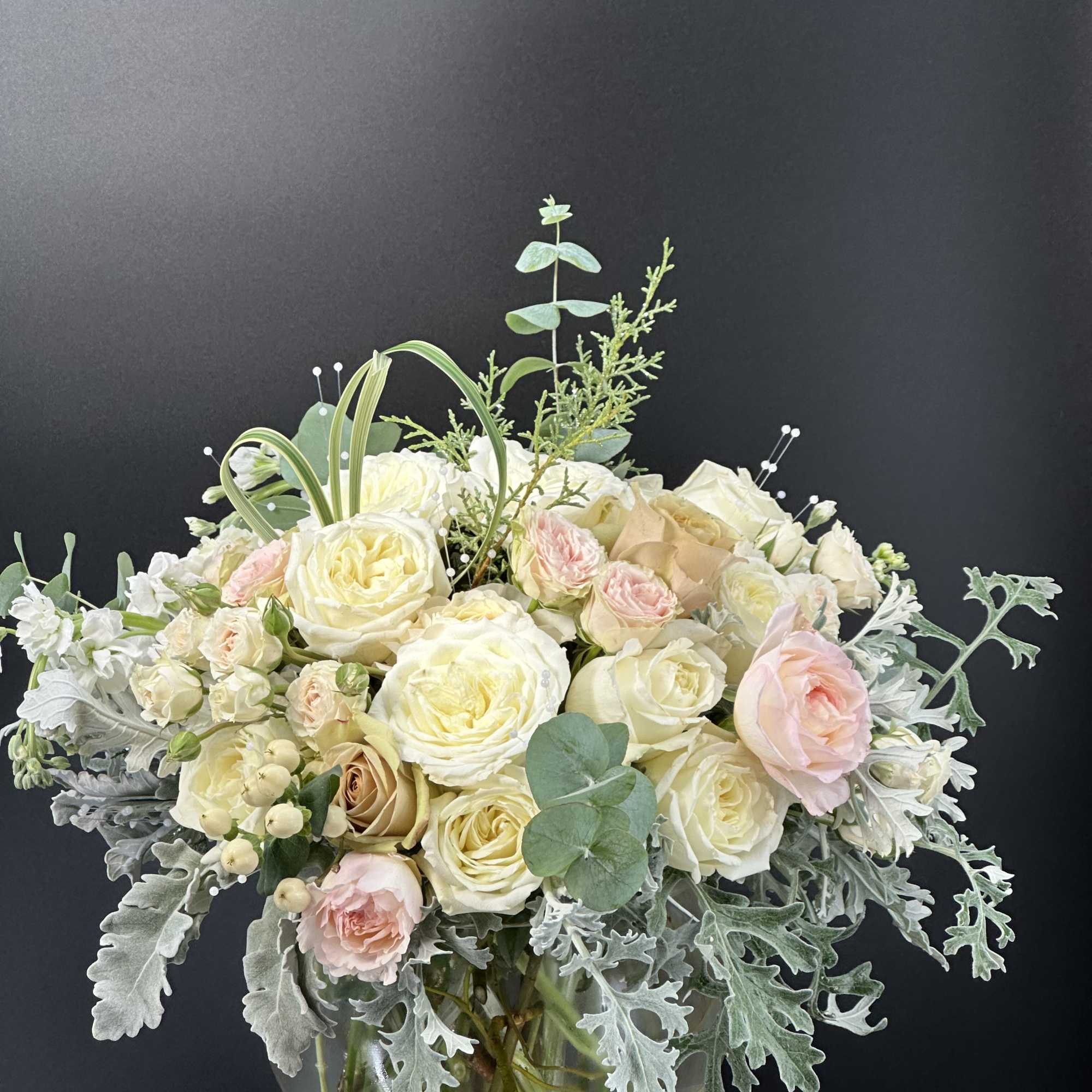 Bouquet of cream and blush roses in a glass vase