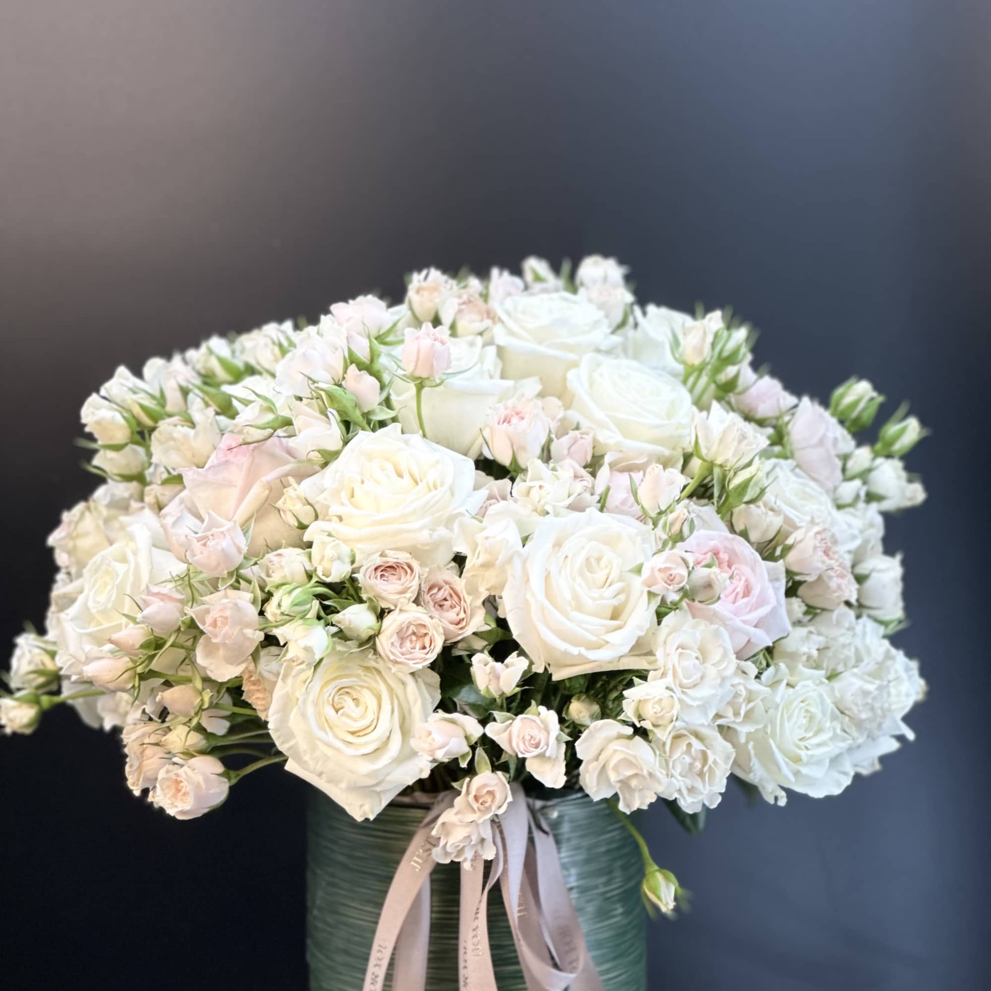 Large bouquet of white and blush roses in a green vase