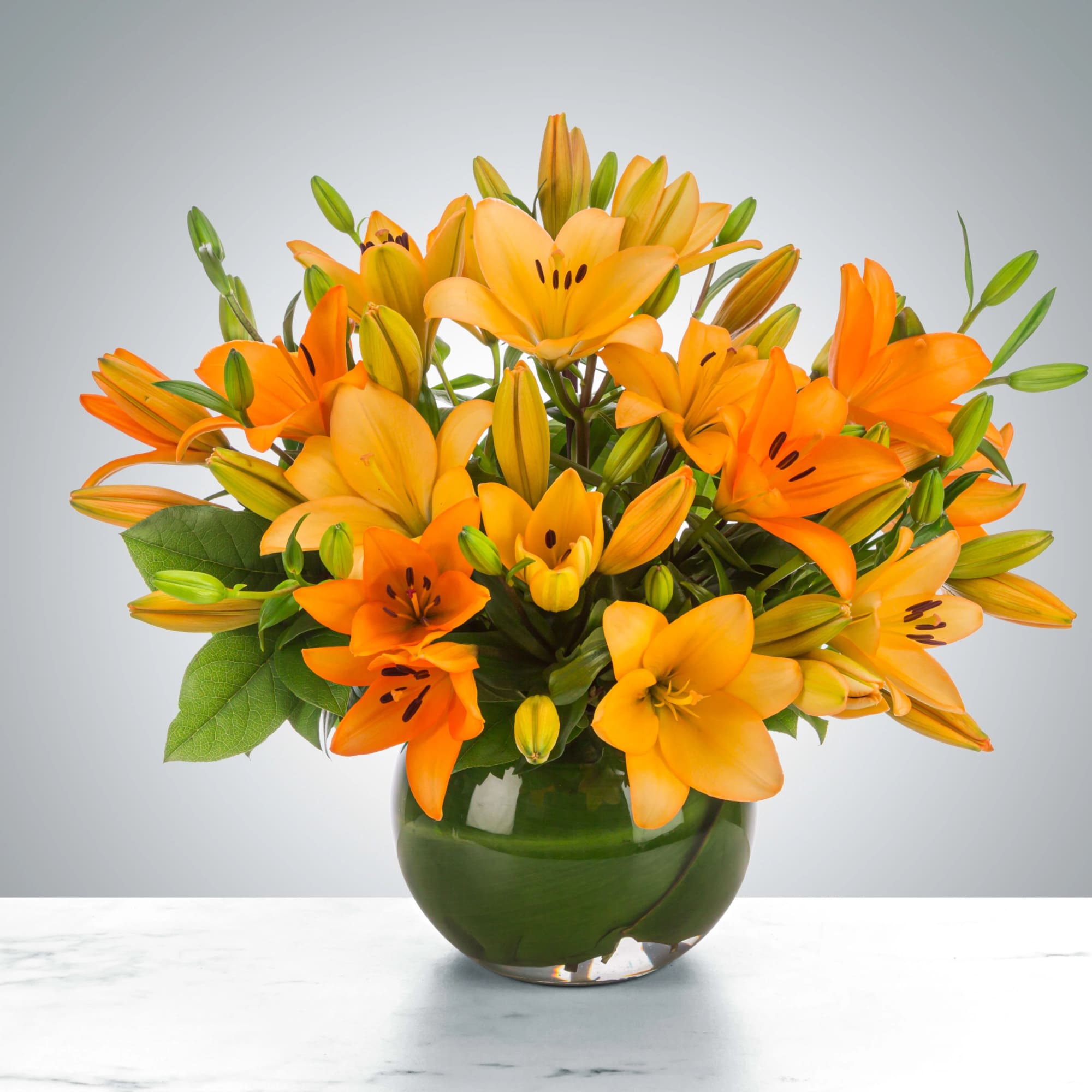 Orange lilies arranged in a green glass vase