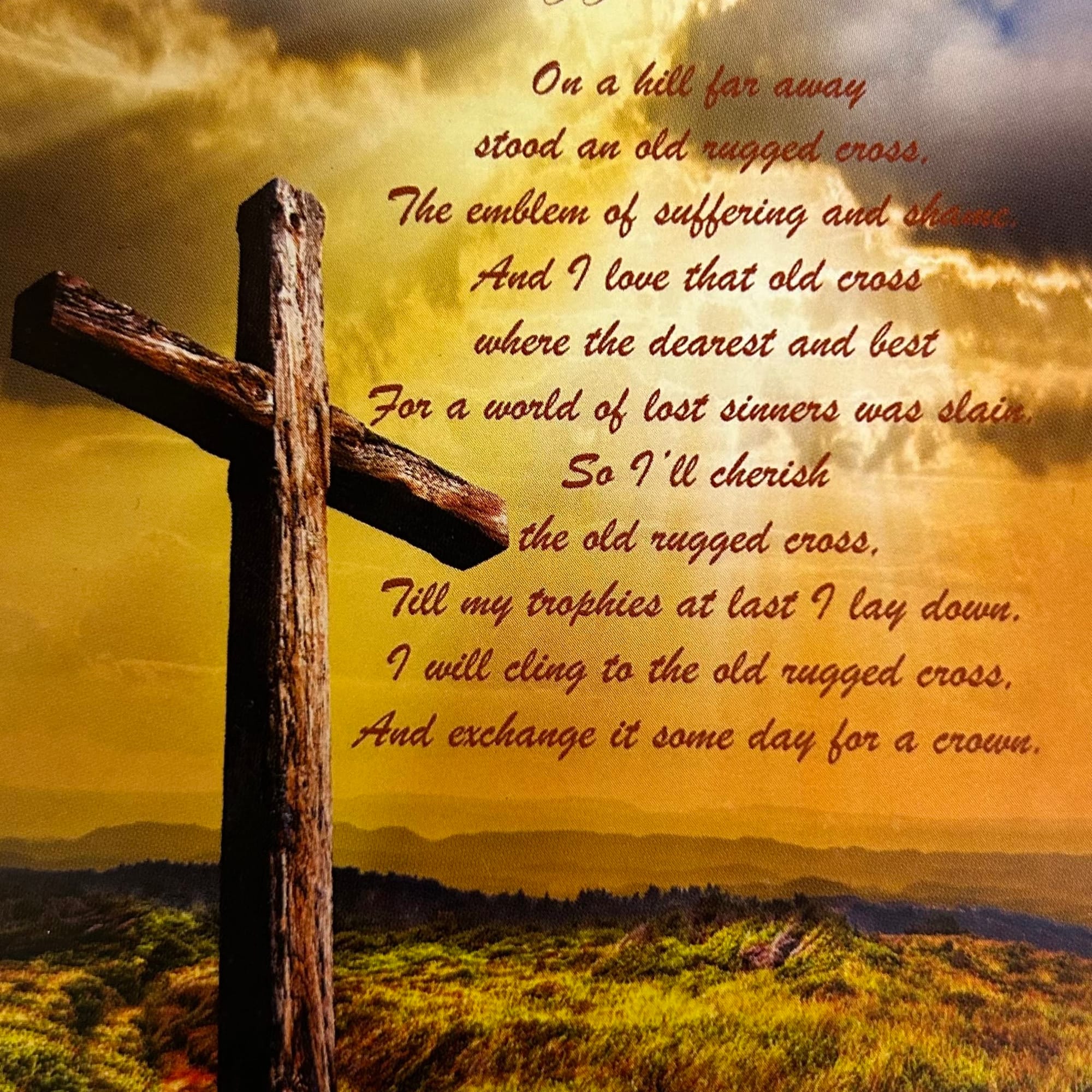A rustic wooden cross against a golden sky with poem text