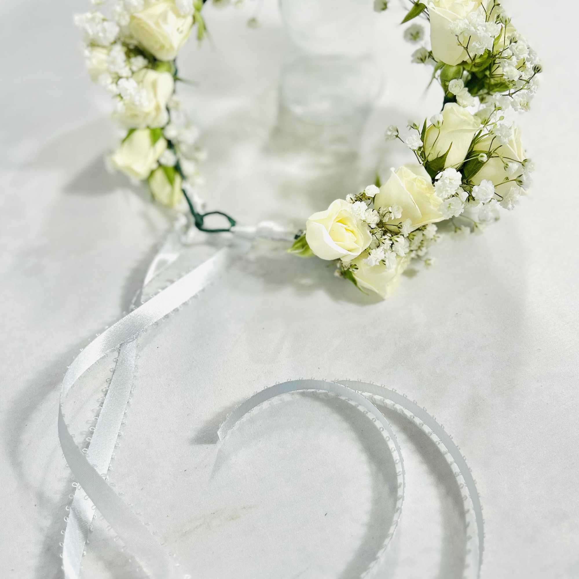 White rose flower crown with ribbon ties on a light background