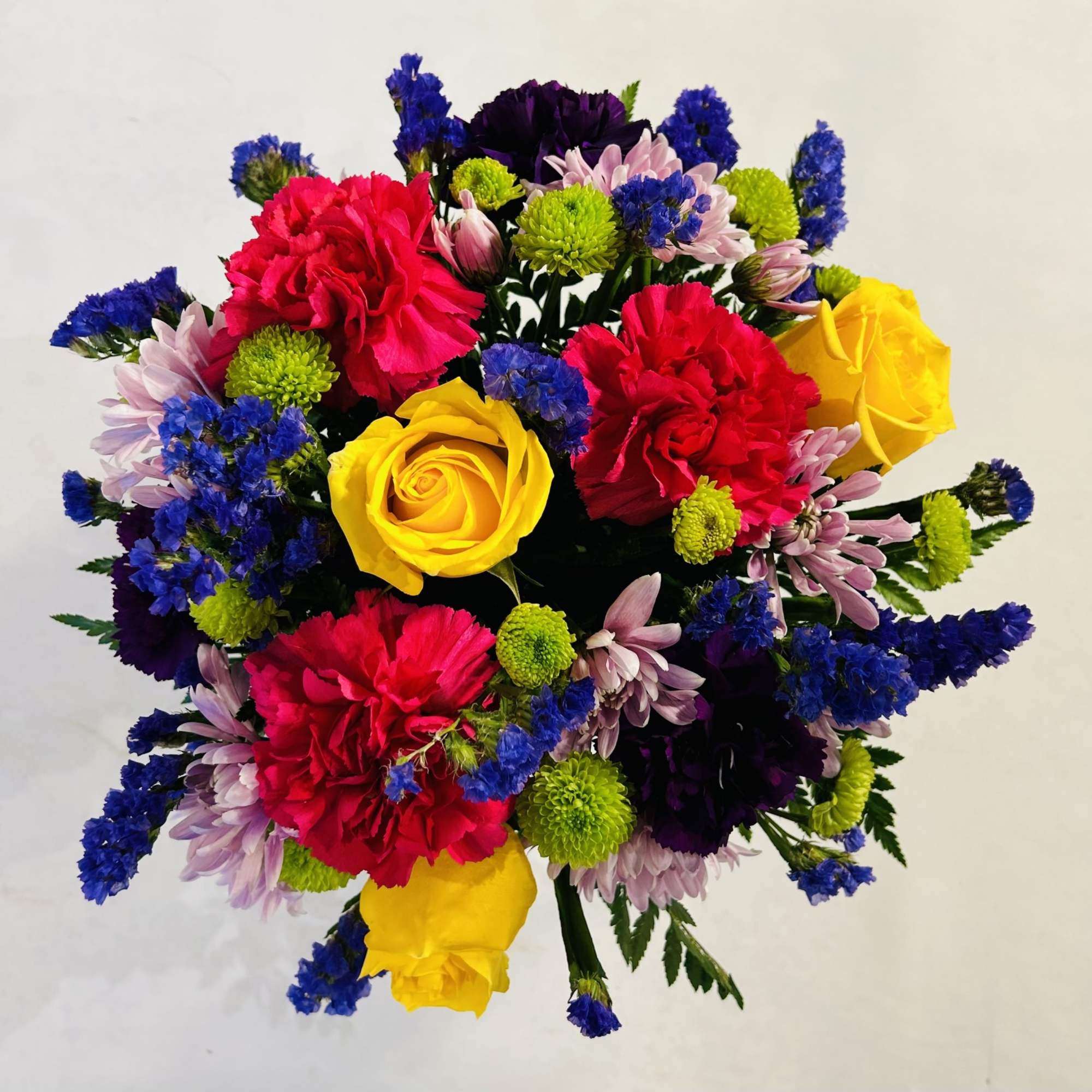 Colorful bouquet with yellow roses, red carnations, and purple flowers