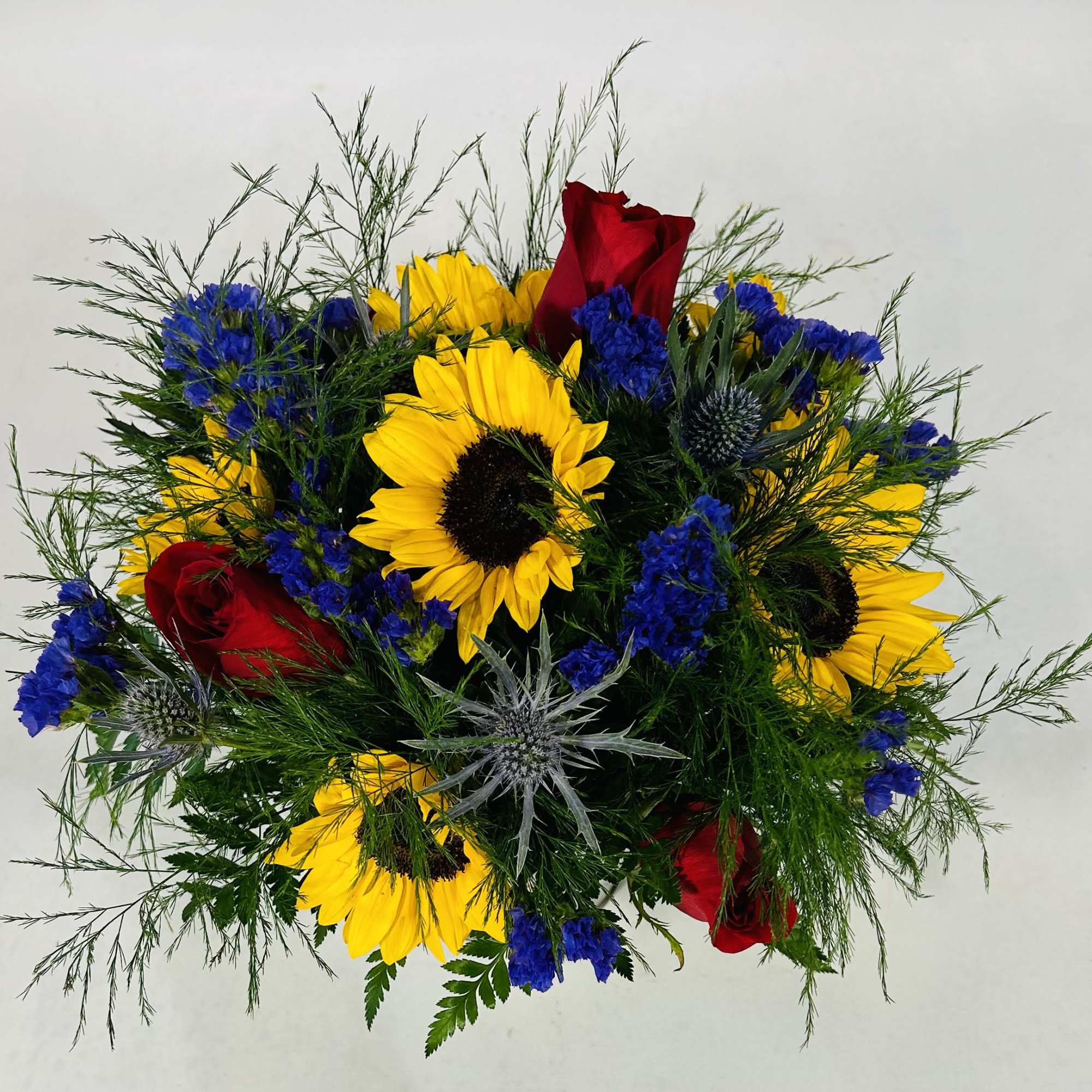 Bouquet of yellow sunflowers, red roses, and blue filler flowers