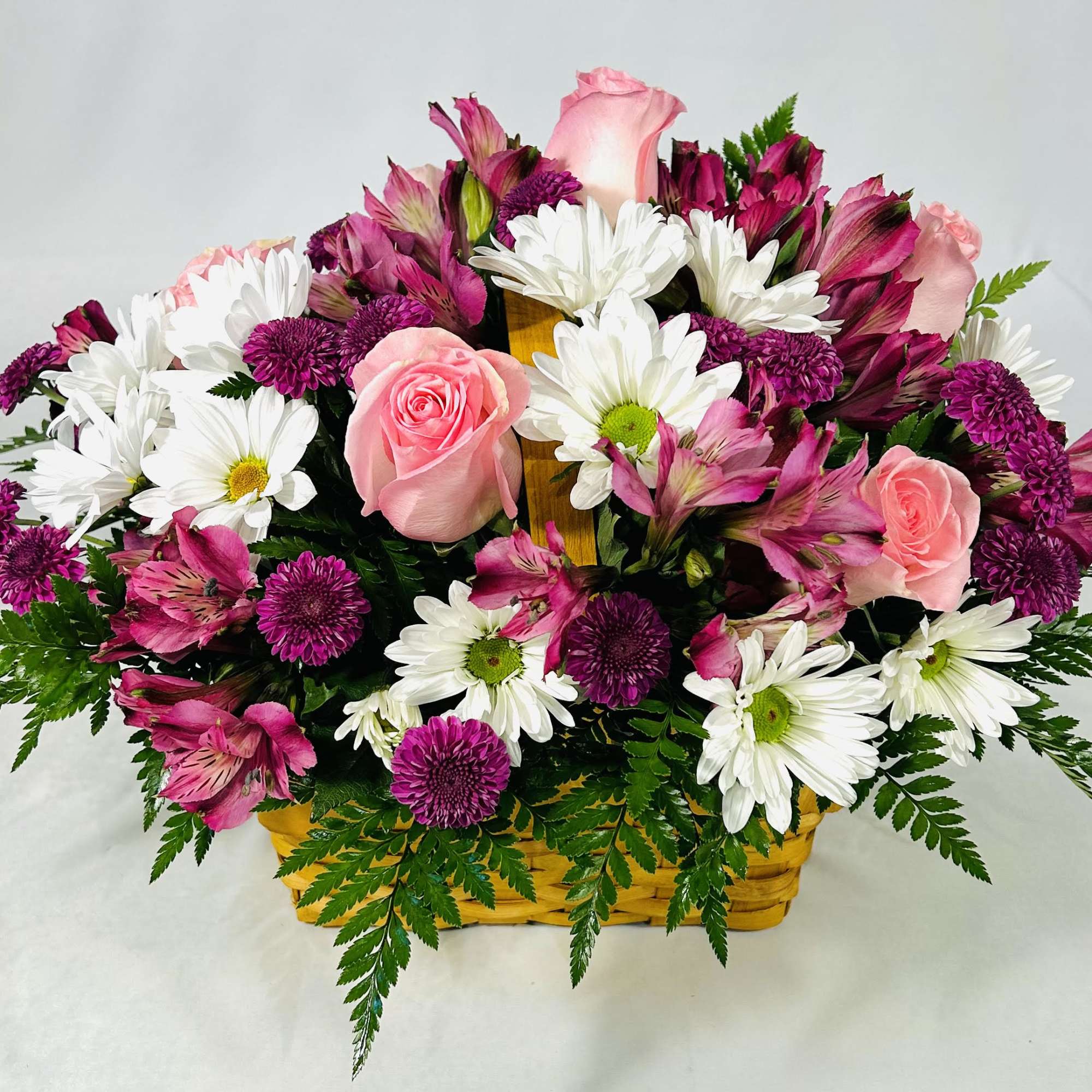 Basket arrangement of pink roses, purple mums, white daisies, and pink alstroemeria
