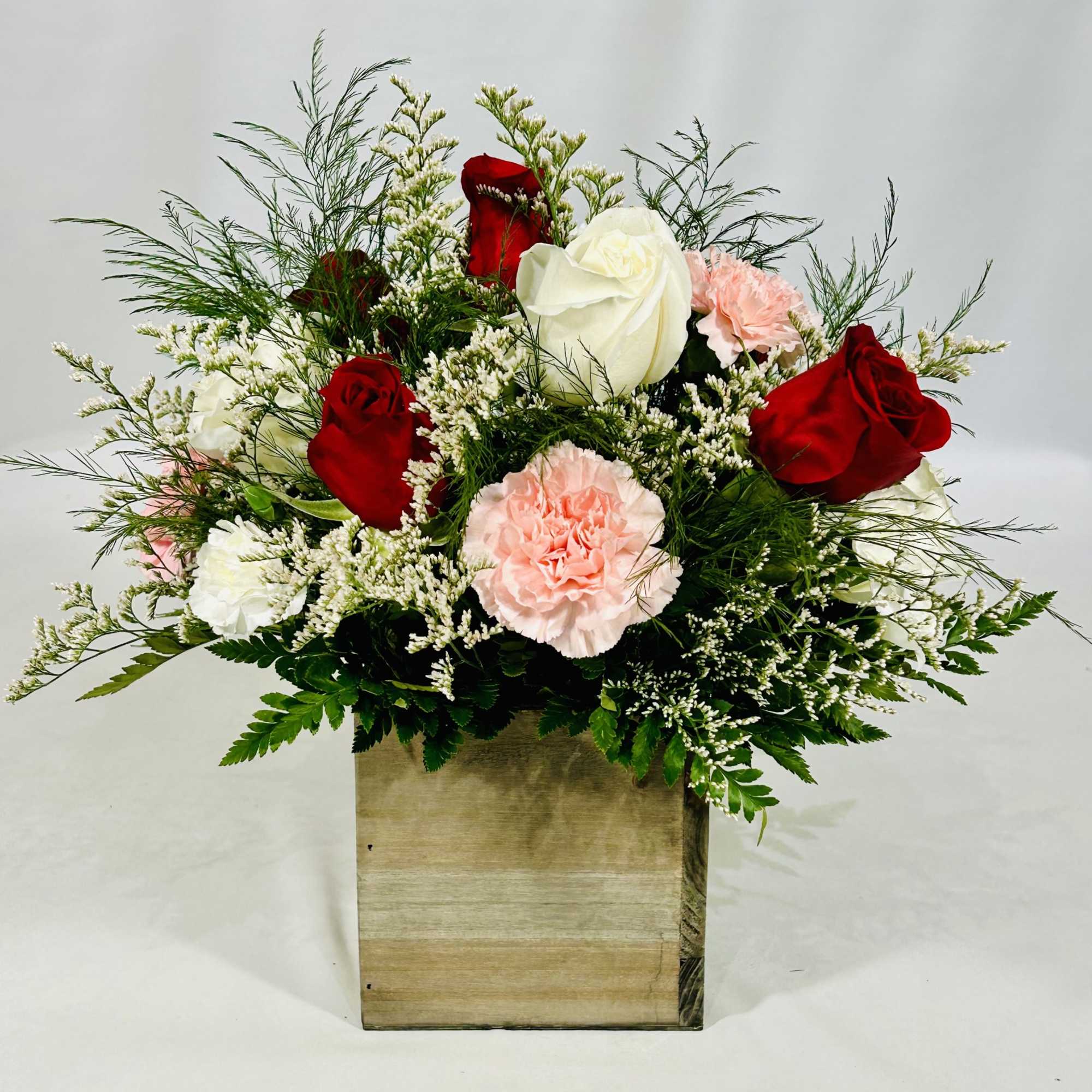 Red and white roses with pink carnations in a wooden box