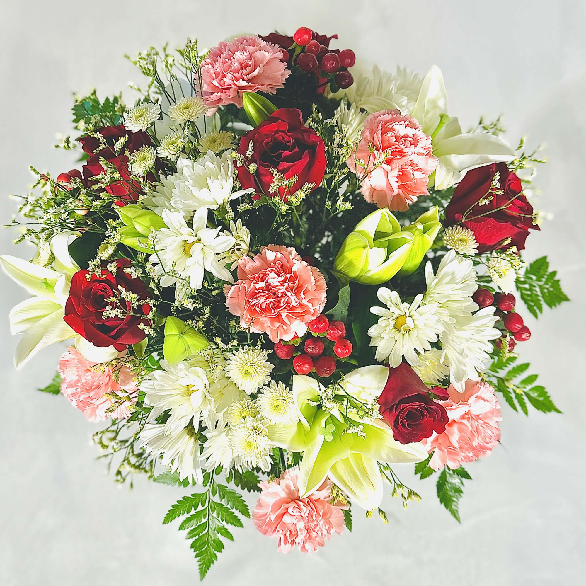 Bouquet of red roses, pink carnations, white daisies, and white lilies