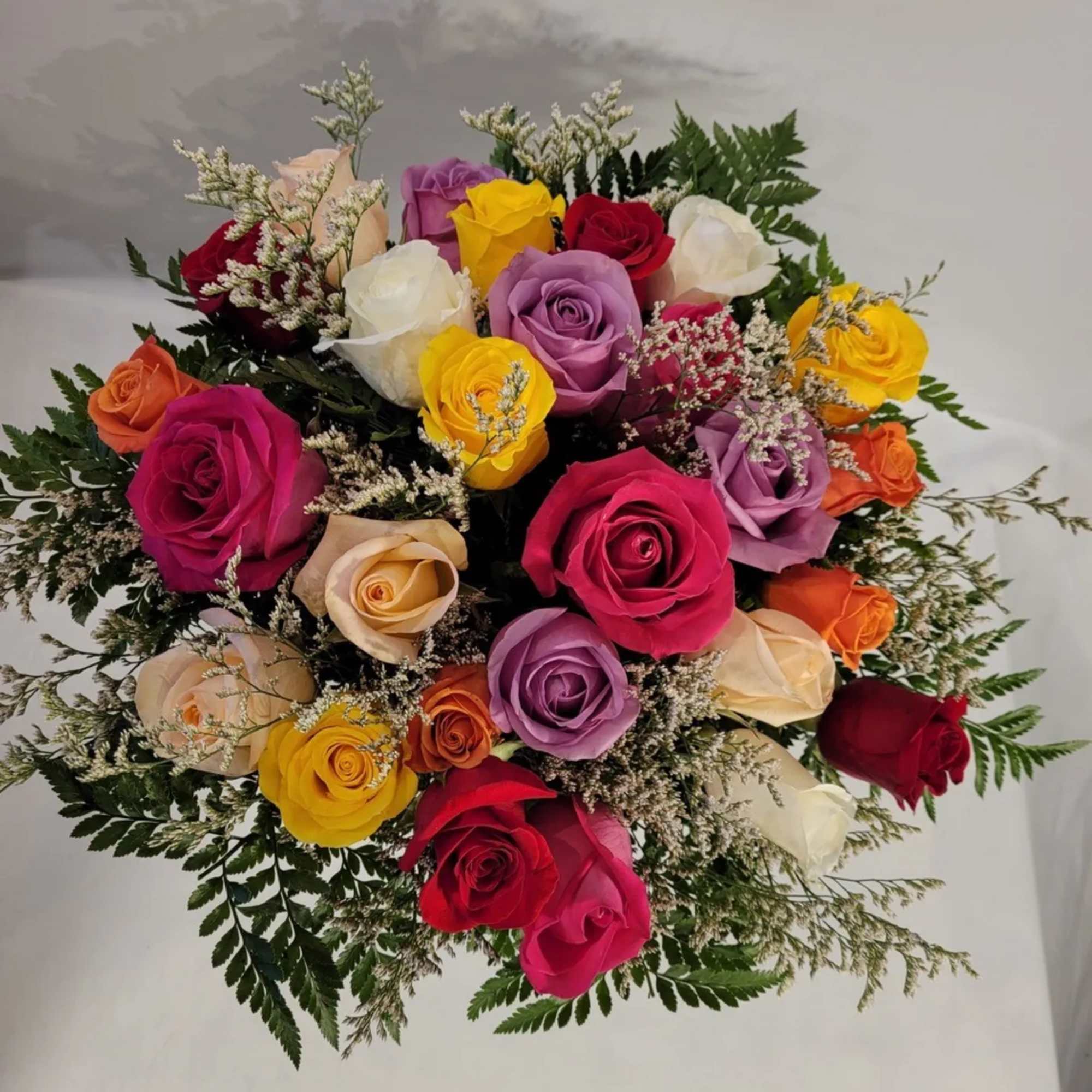 A full, cheerful bouquet of mixed roses in red, yellow, orange, pink