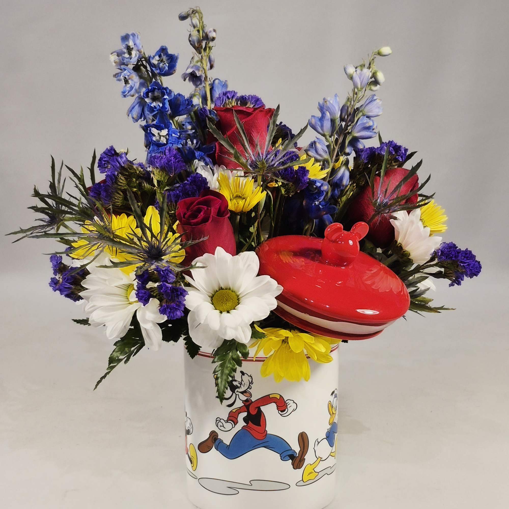 Mixed bouquet in a Disney-themed mug with a red lidded container