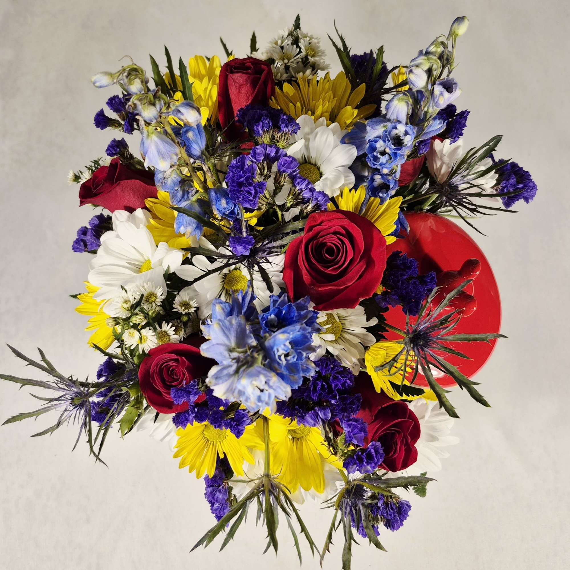 Mixed bouquet of red roses, daisies, and blue flowers