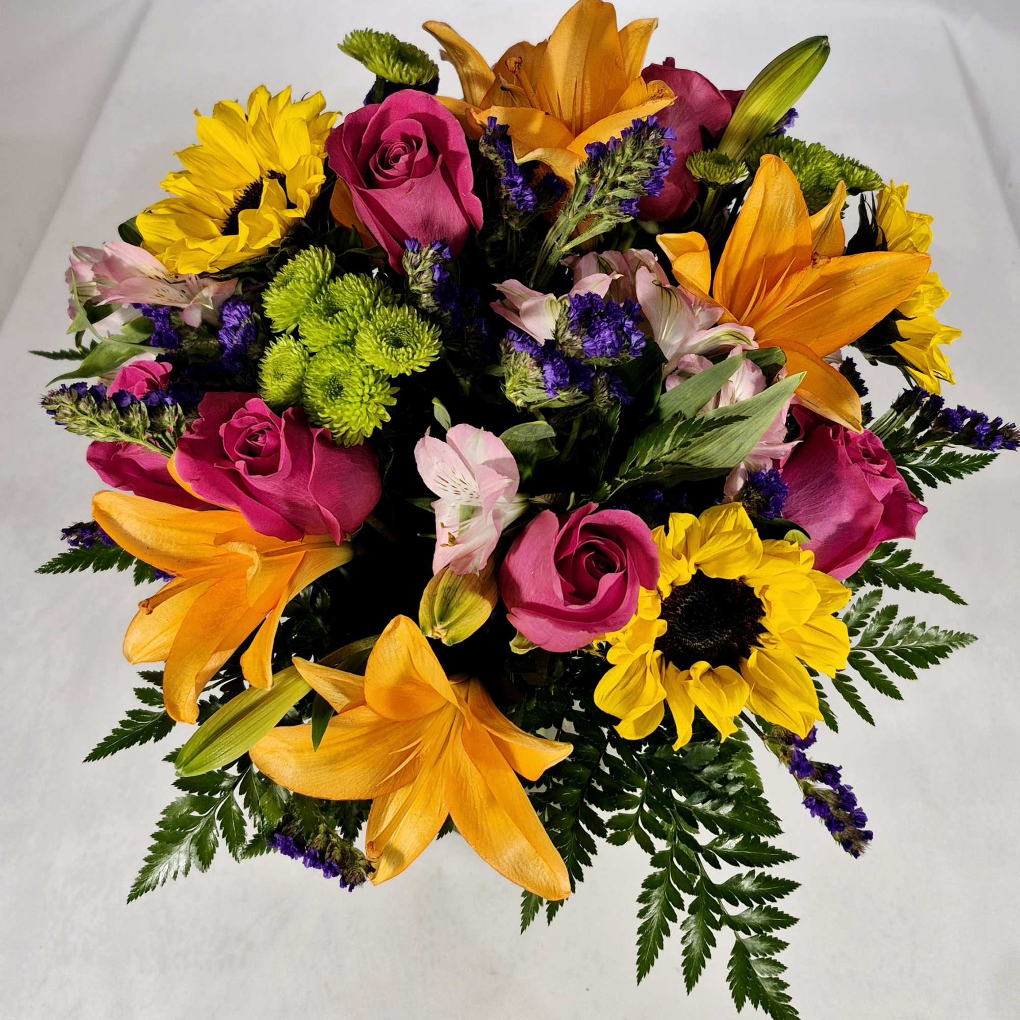Bouquet of pink roses, orange lilies, and yellow sunflowers