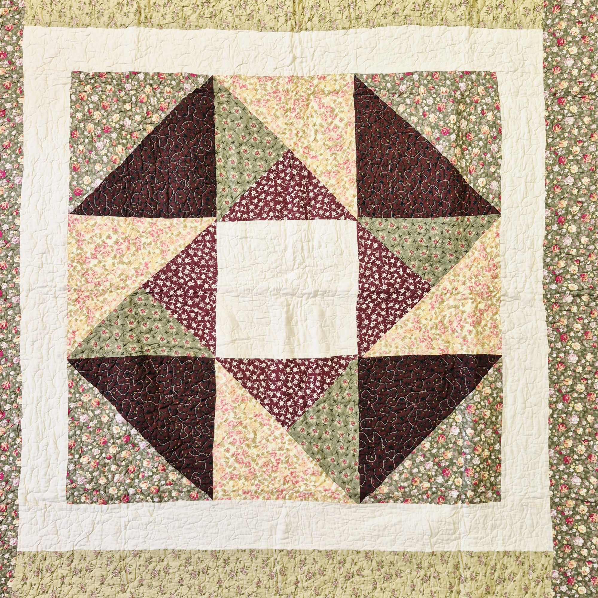 Patchwork quilt with floral prints in burgundy, green, and cream
