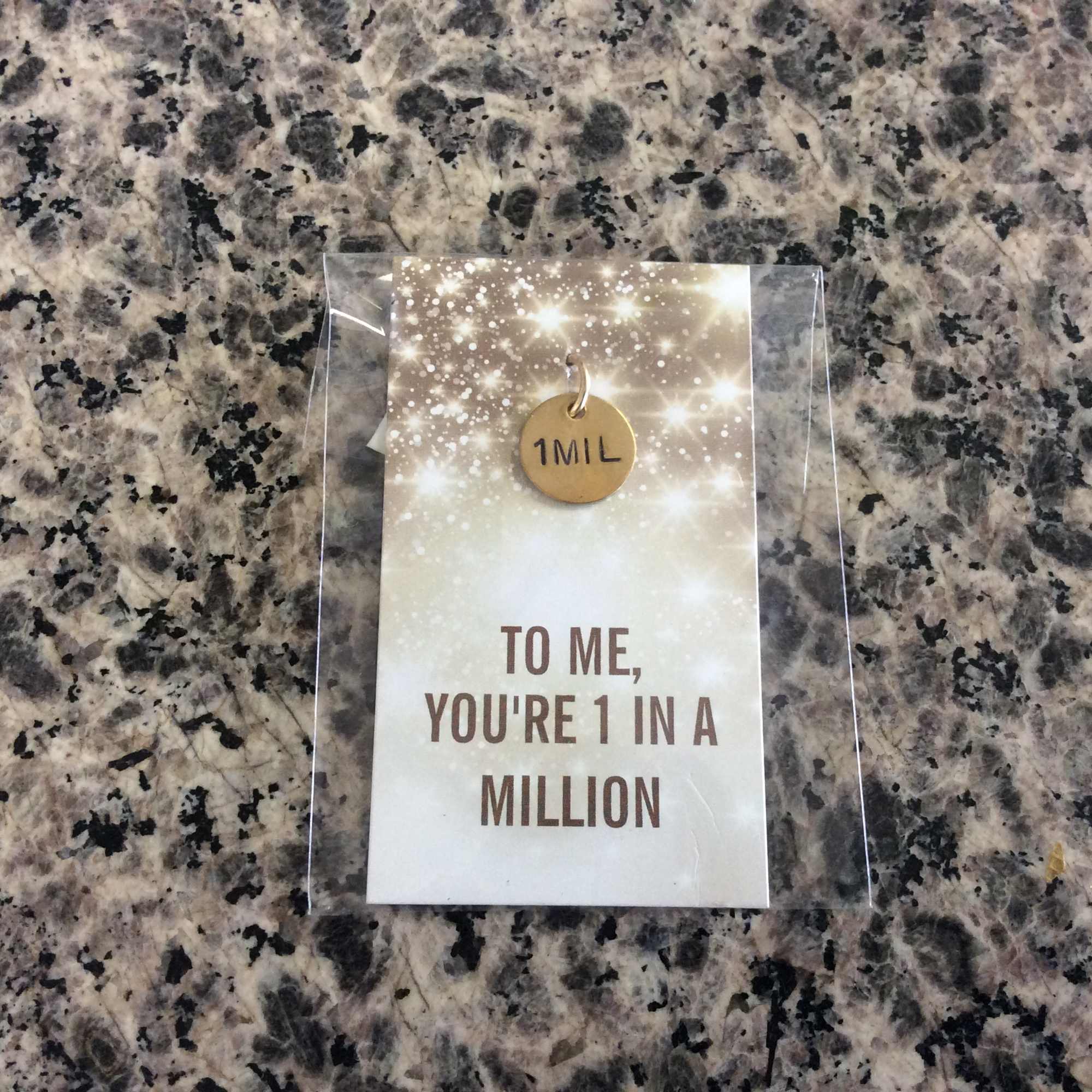 Gift card in a clear sleeve with a gold tag reading "1MIL"
