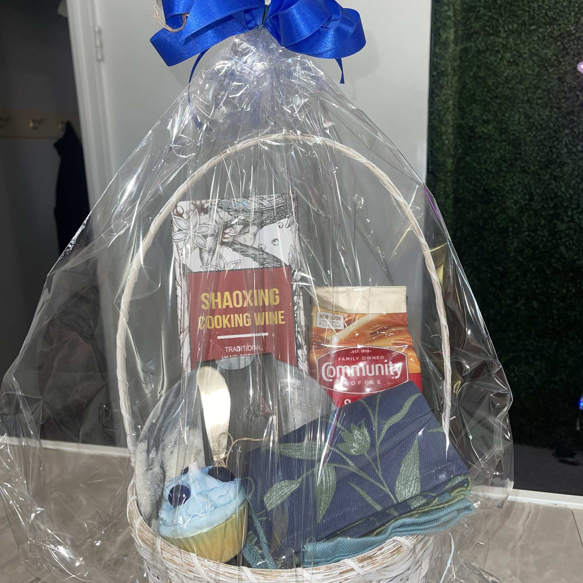 Gift basket with cooking wine, coffee, a folded cloth, and a cupcake