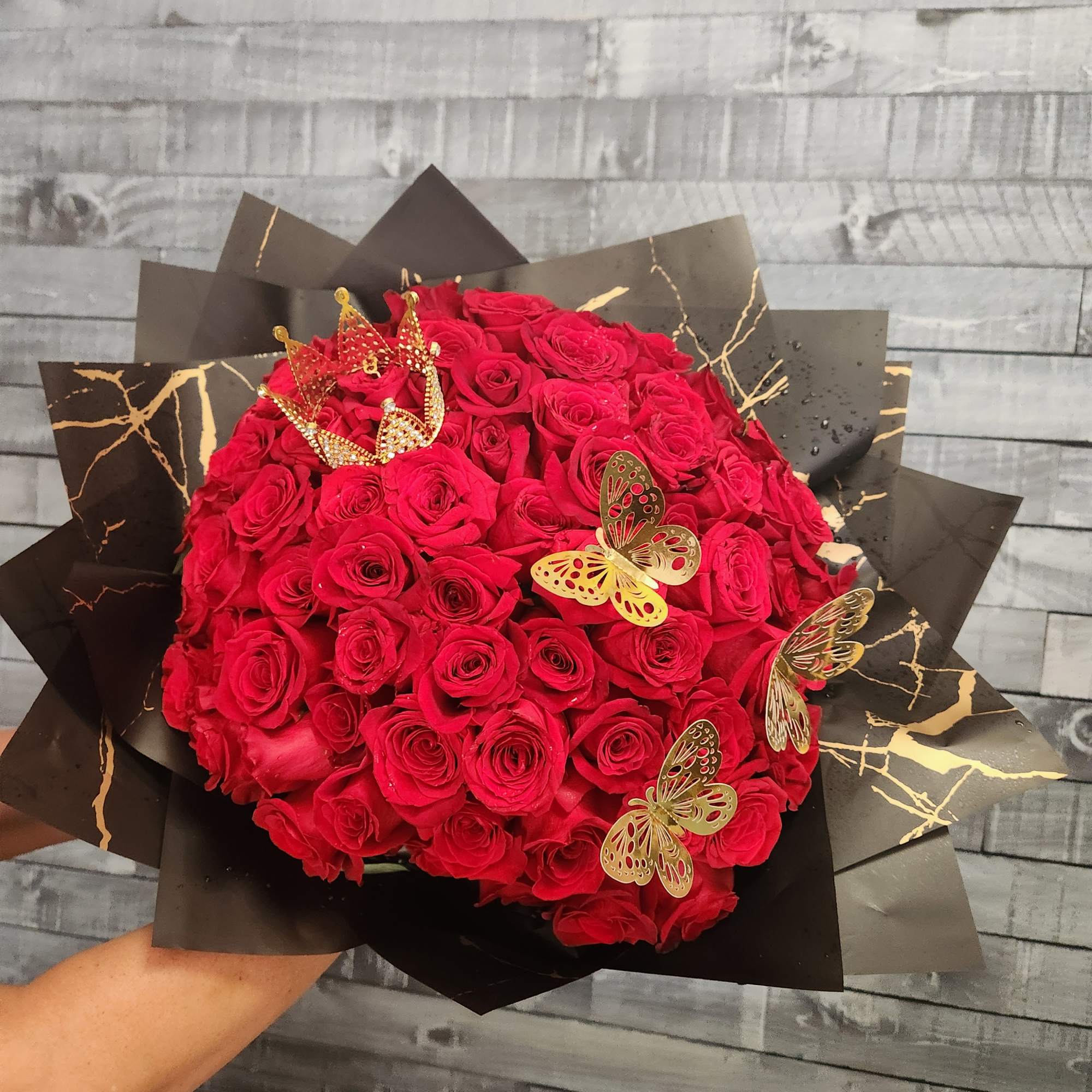 Large bouquet of red roses wrapped in black paper with gold accents