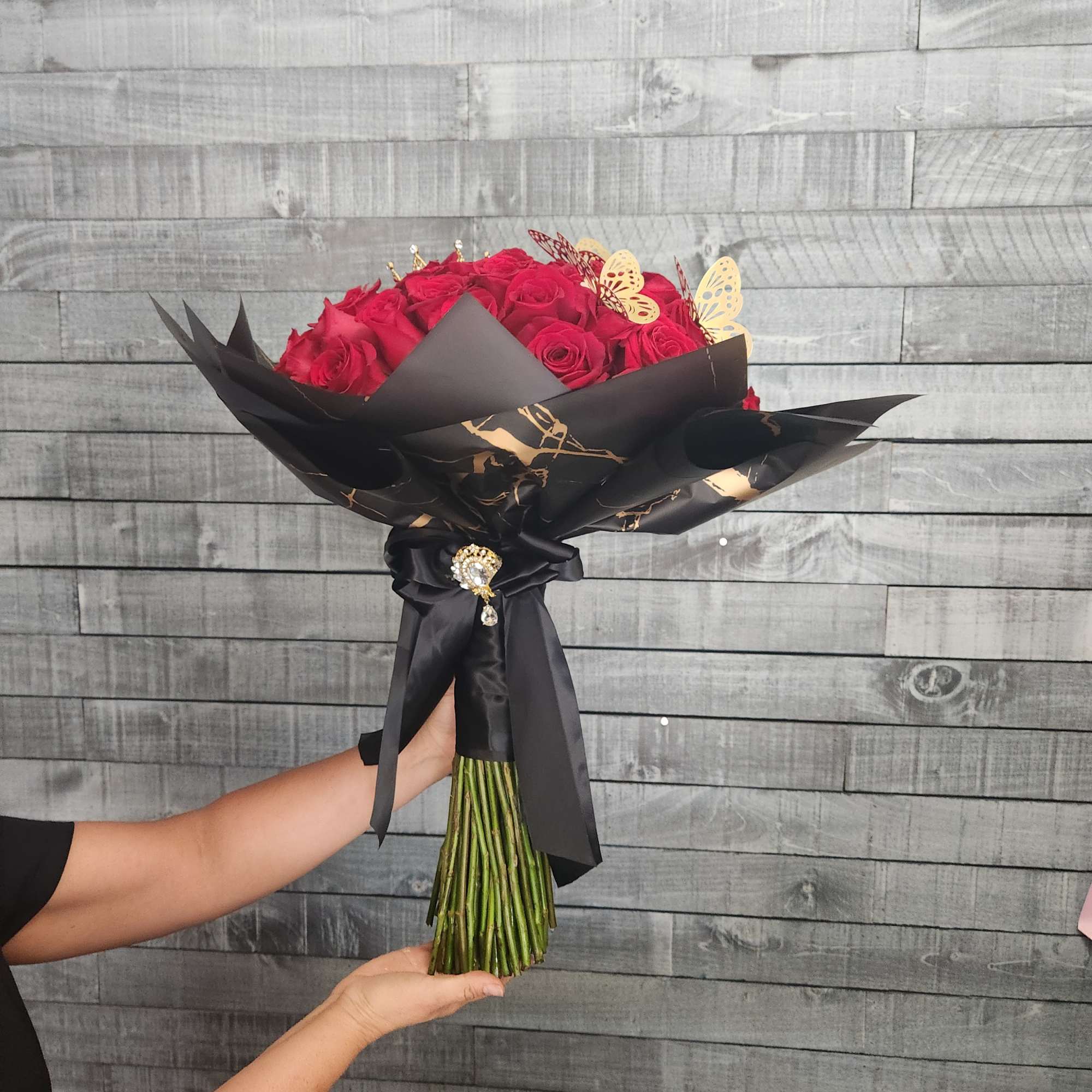Bouquet of red roses wrapped in black paper with butterfly accents