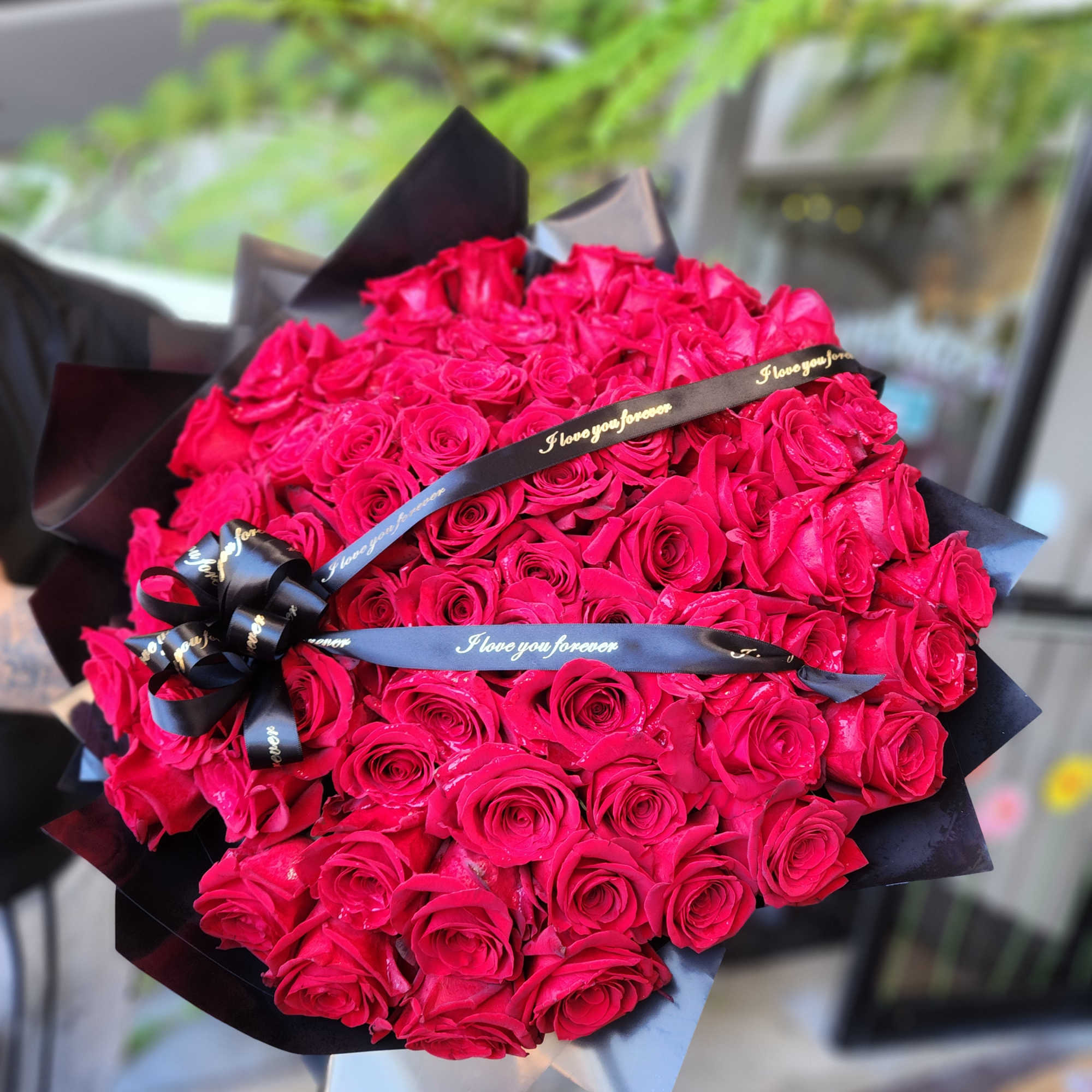 Large bouquet of hot pink roses wrapped in black paper with ribbon