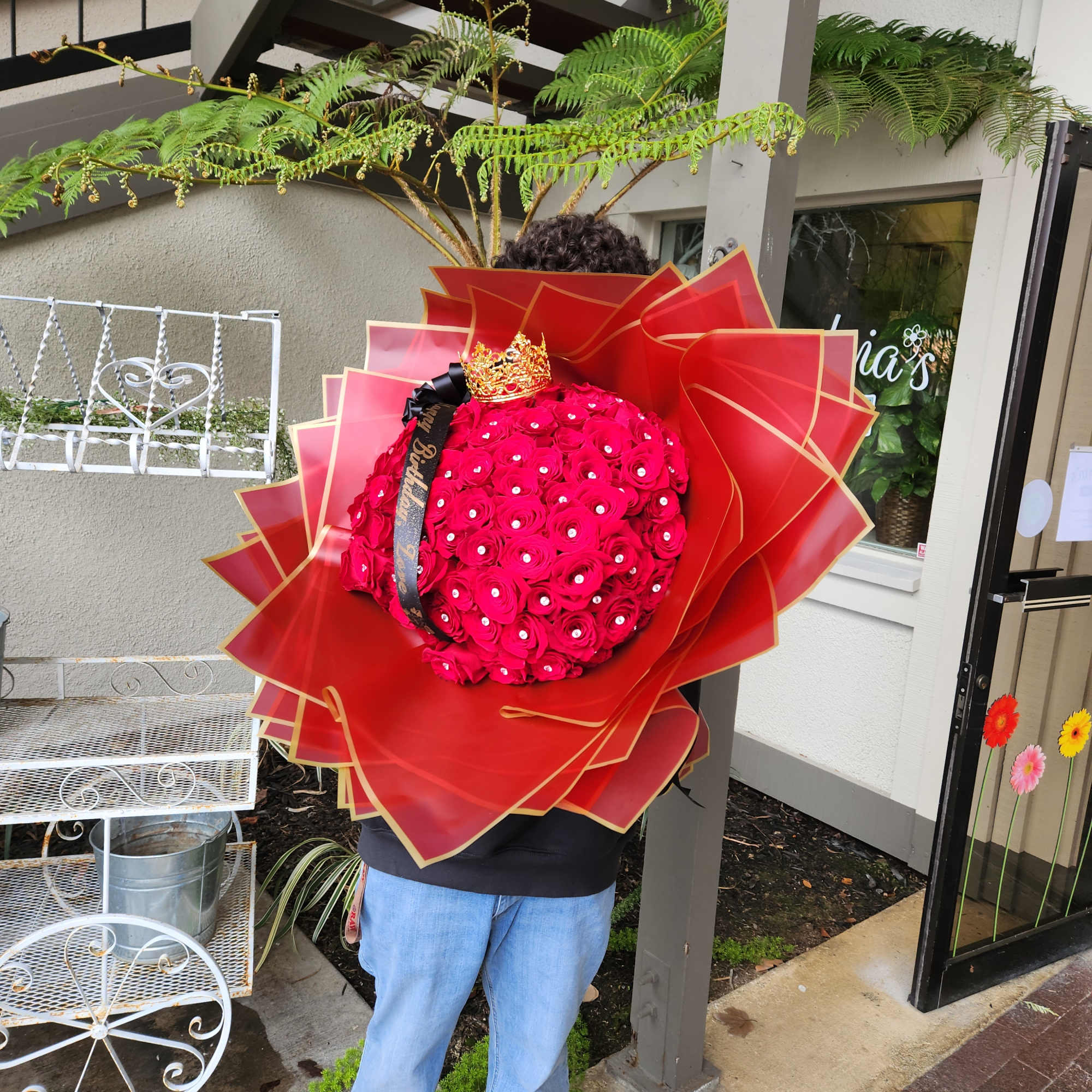 Large bouquet of hot pink roses wrapped in red paper with a crown topper