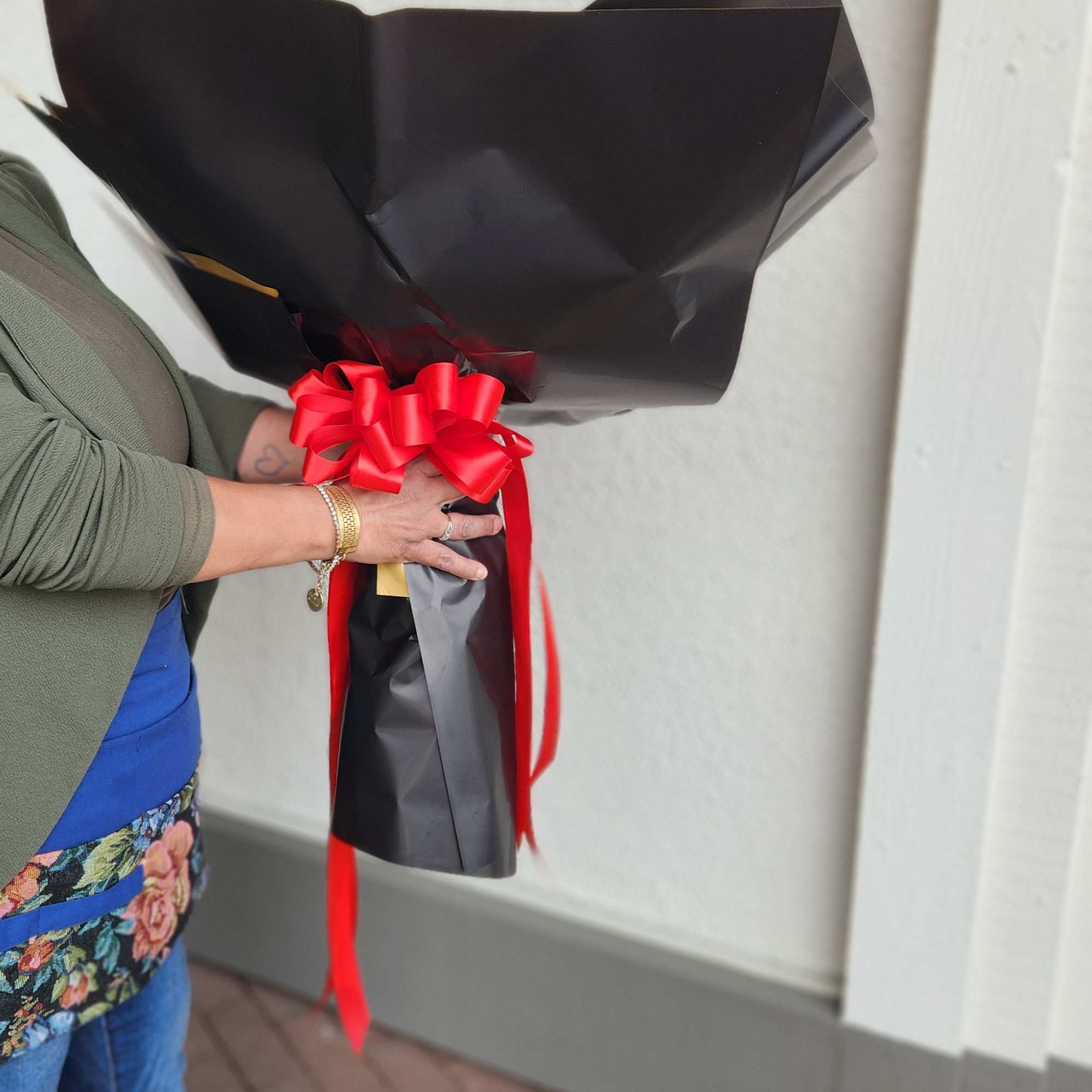 Wrapped bouquet with black paper and a red ribbon bow