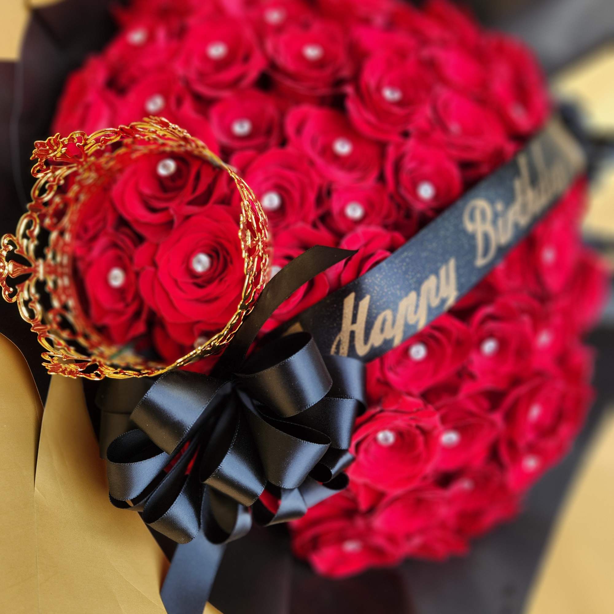 Bouquet of red roses with a black ribbon and gold crown decoration