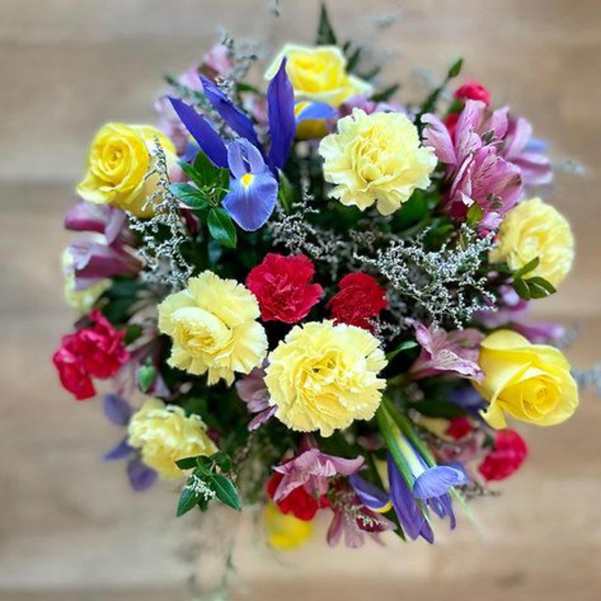 Mixed bouquet of yellow roses, carnations, and purple flowers