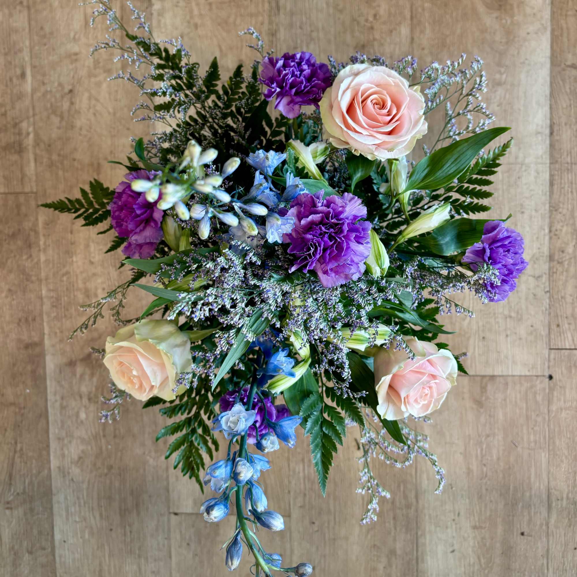 Bouquet of pink roses, purple carnations, and blue flowers