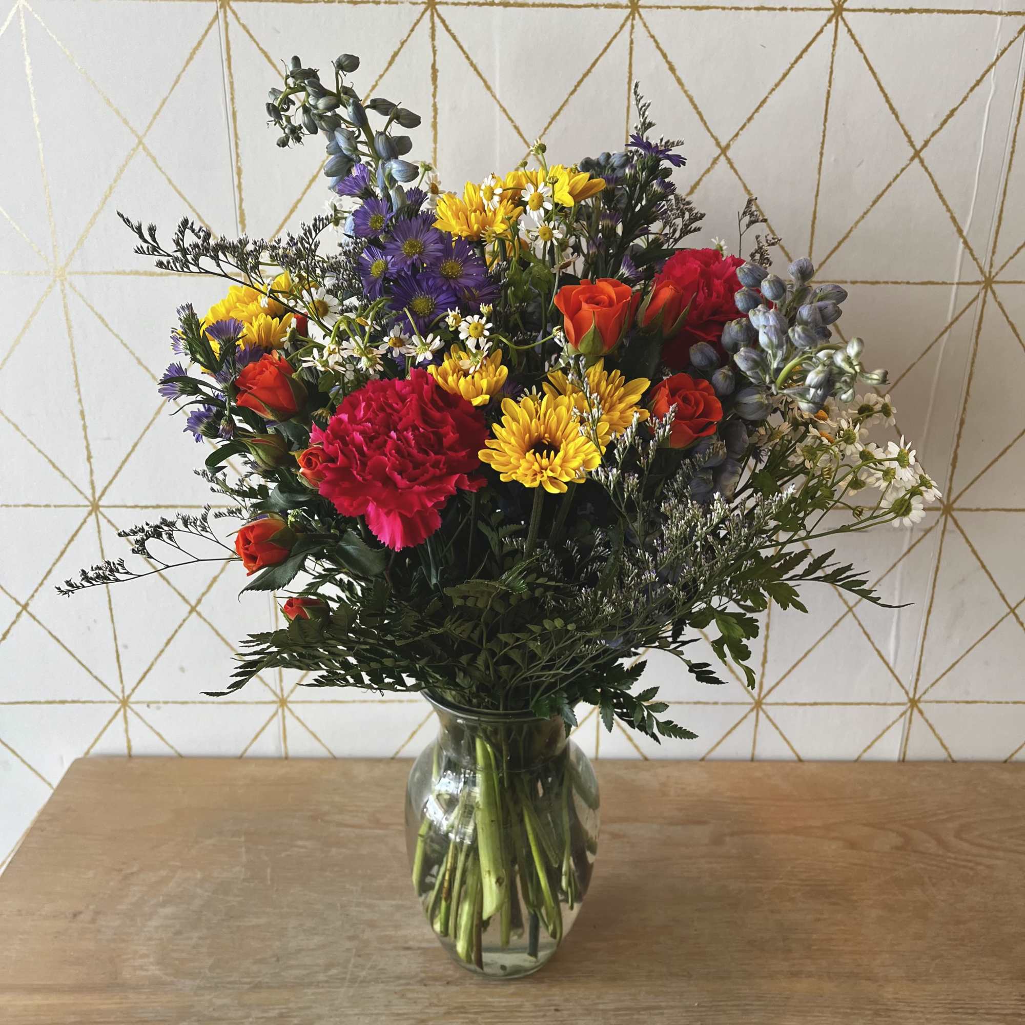 Mixed bouquet of roses, carnations, and daisies in a glass vase