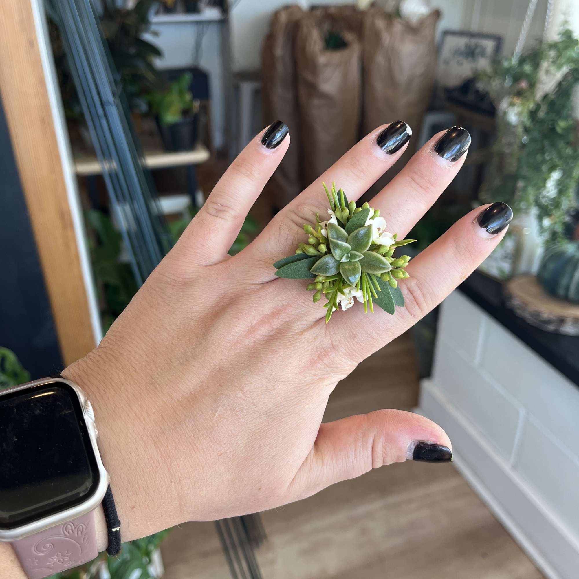 Small succulent ring with tiny white flowers on a hand
