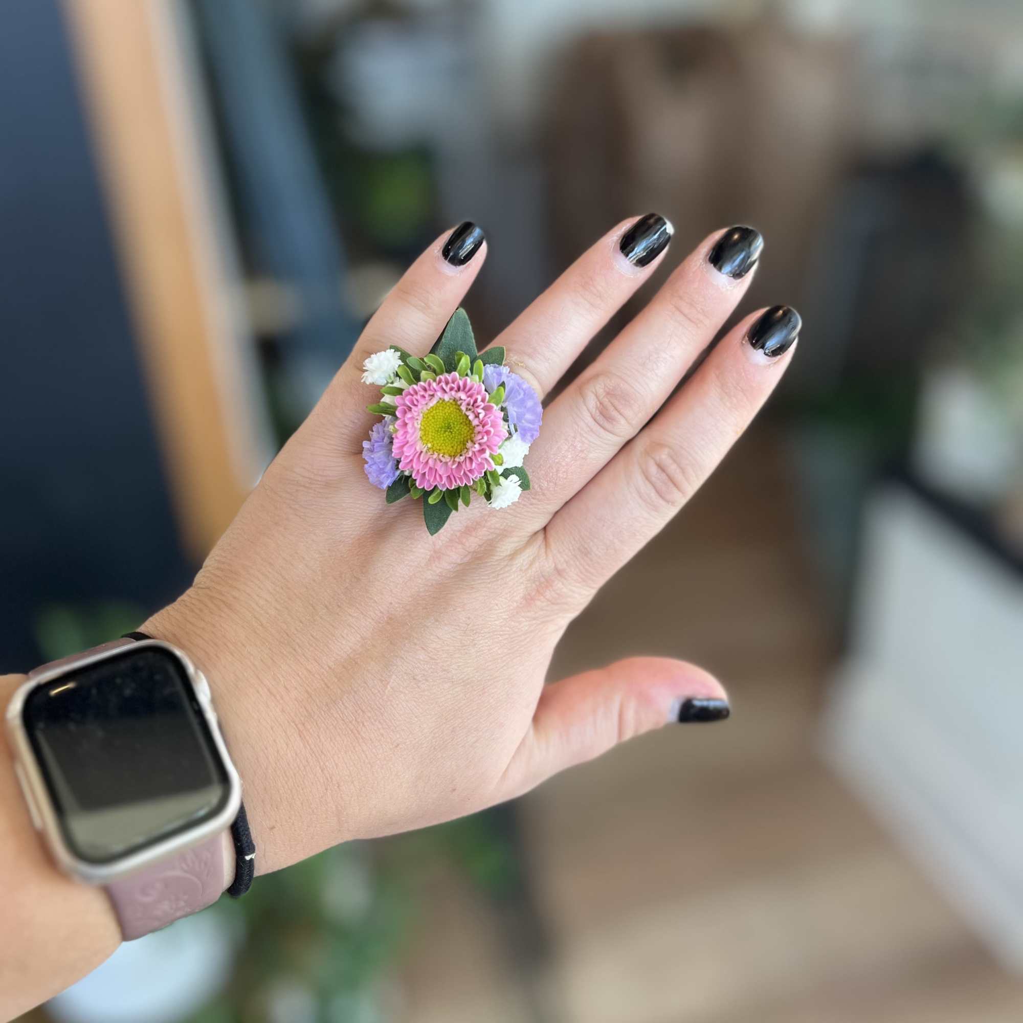 Small floral ring with pink and lavender blooms on a hand
