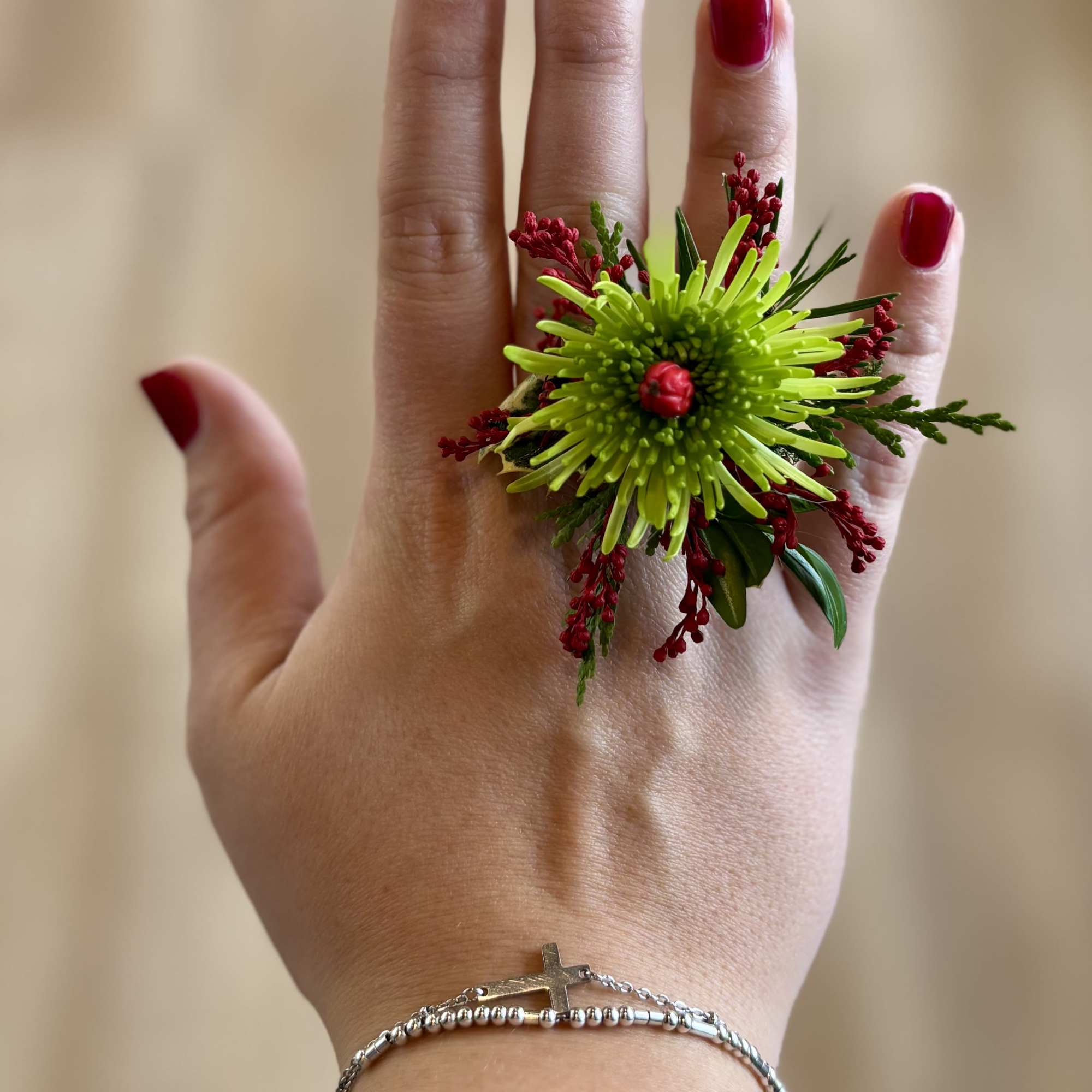 Hand wearing a bright green and red floral ring