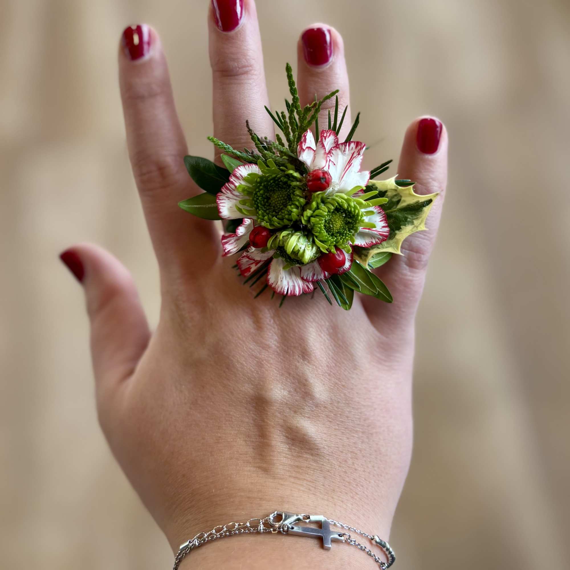 Small floral ring with red, white, and green blooms on a hand