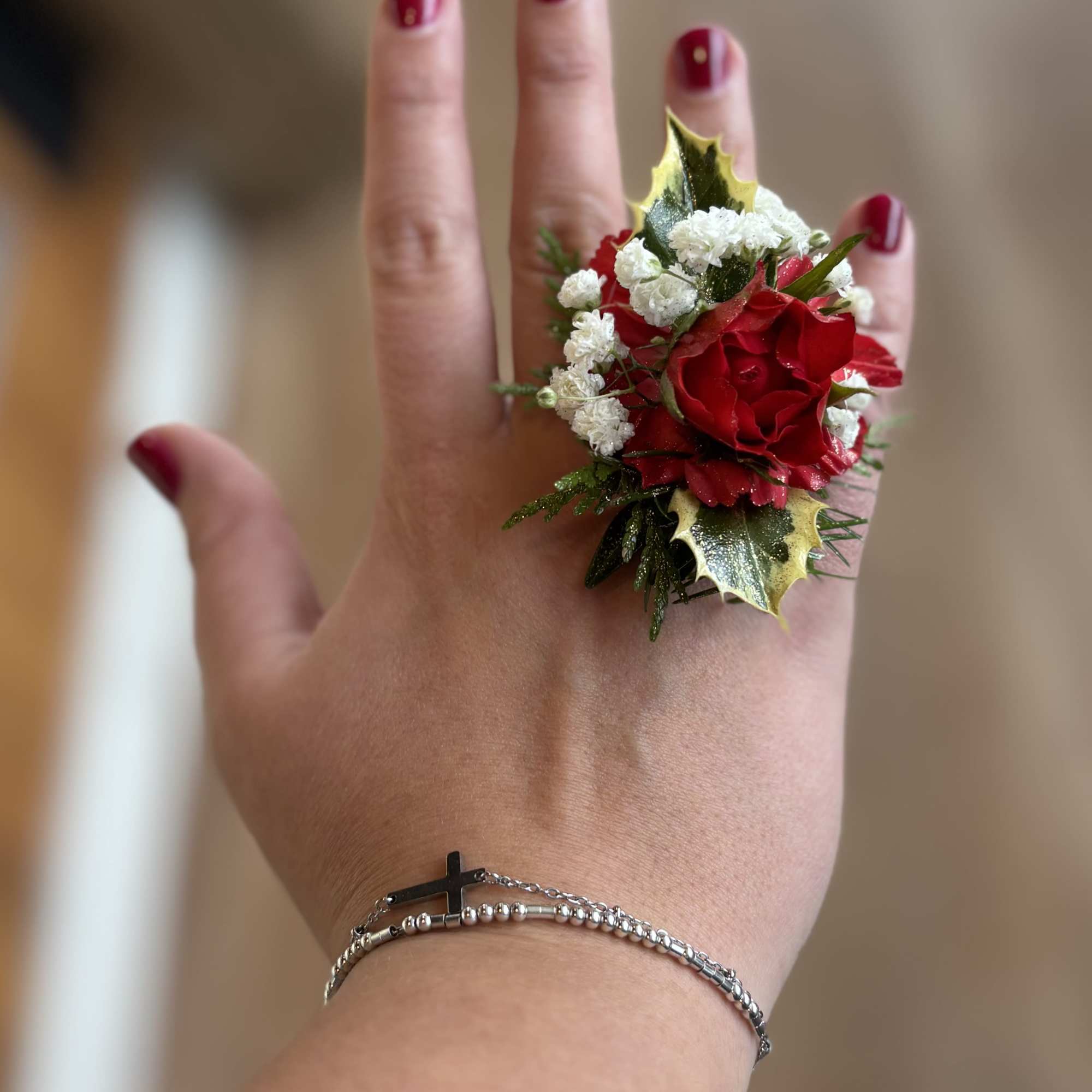 Small red rose corsage on a hand with white filler flowers