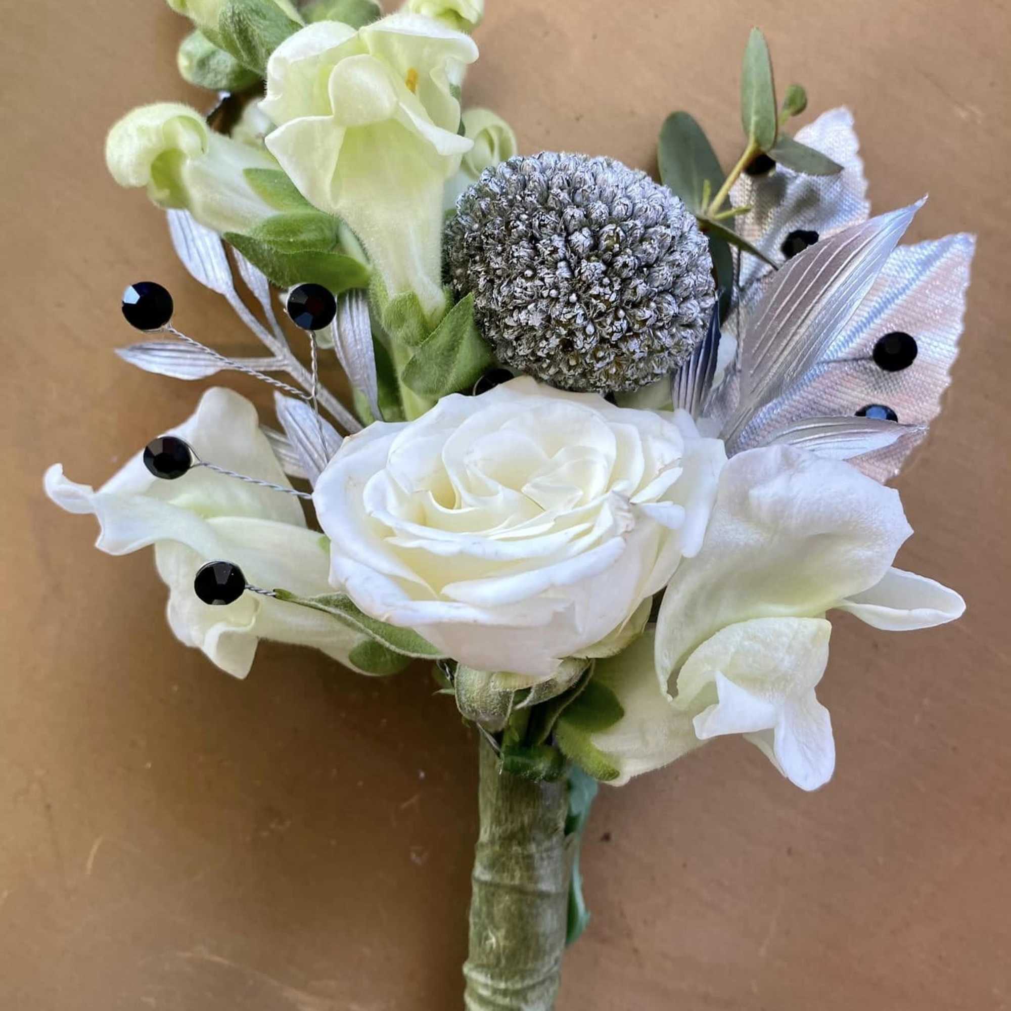 White rose boutonniere with pale calla lilies and silver accents