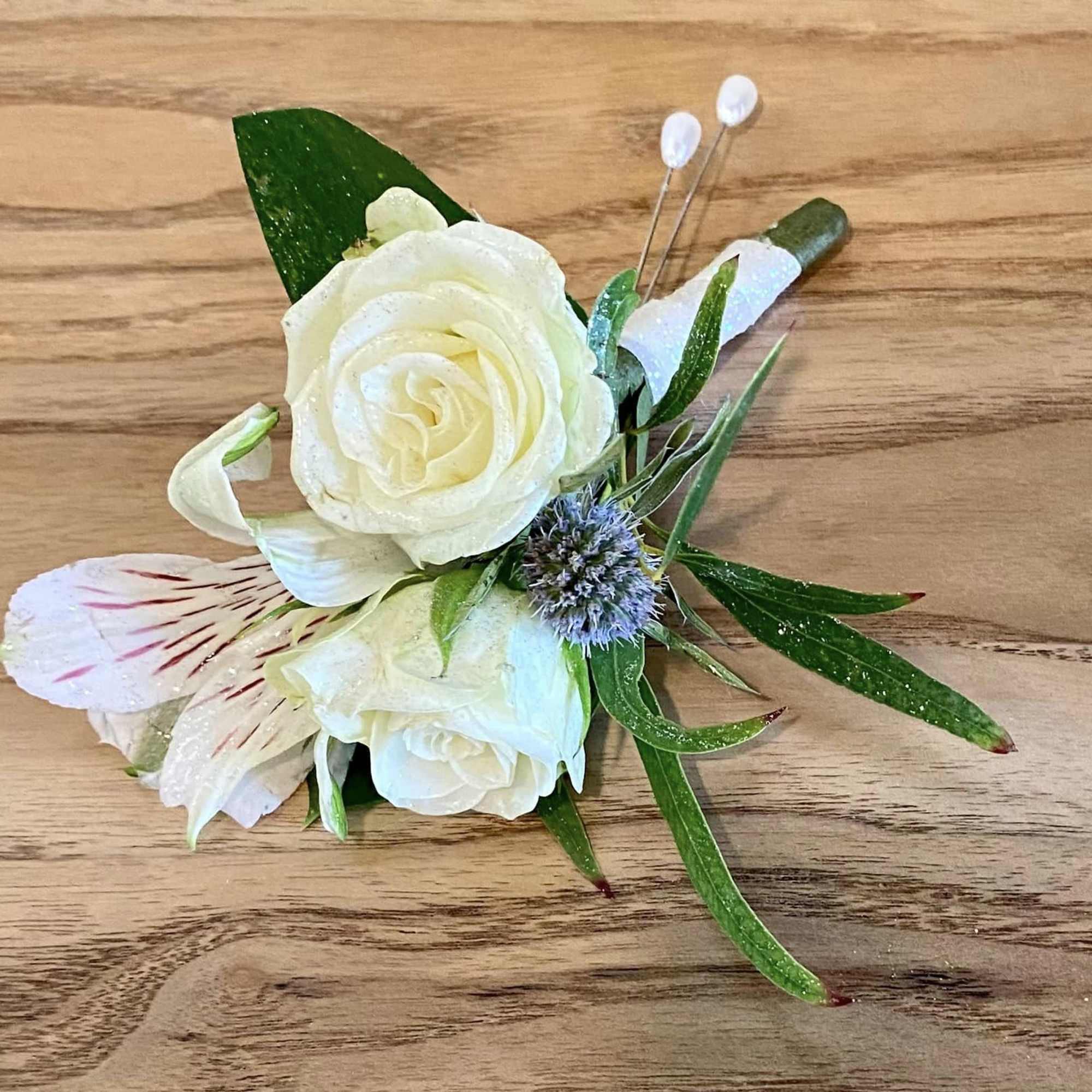 White rose boutonniere with small white and purple accent flowers
