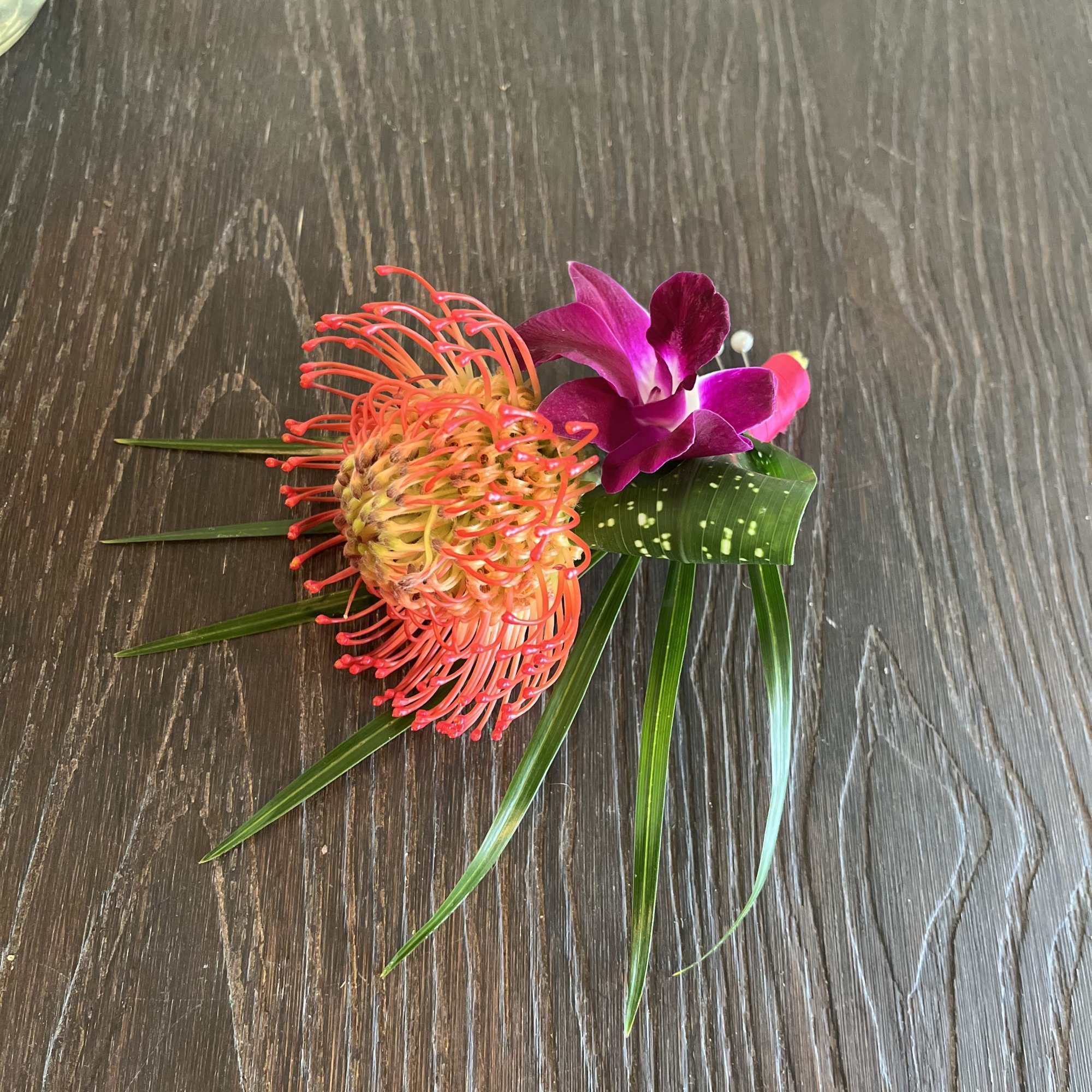 Tropical boutonniere with orange pincushion protea and purple orchid