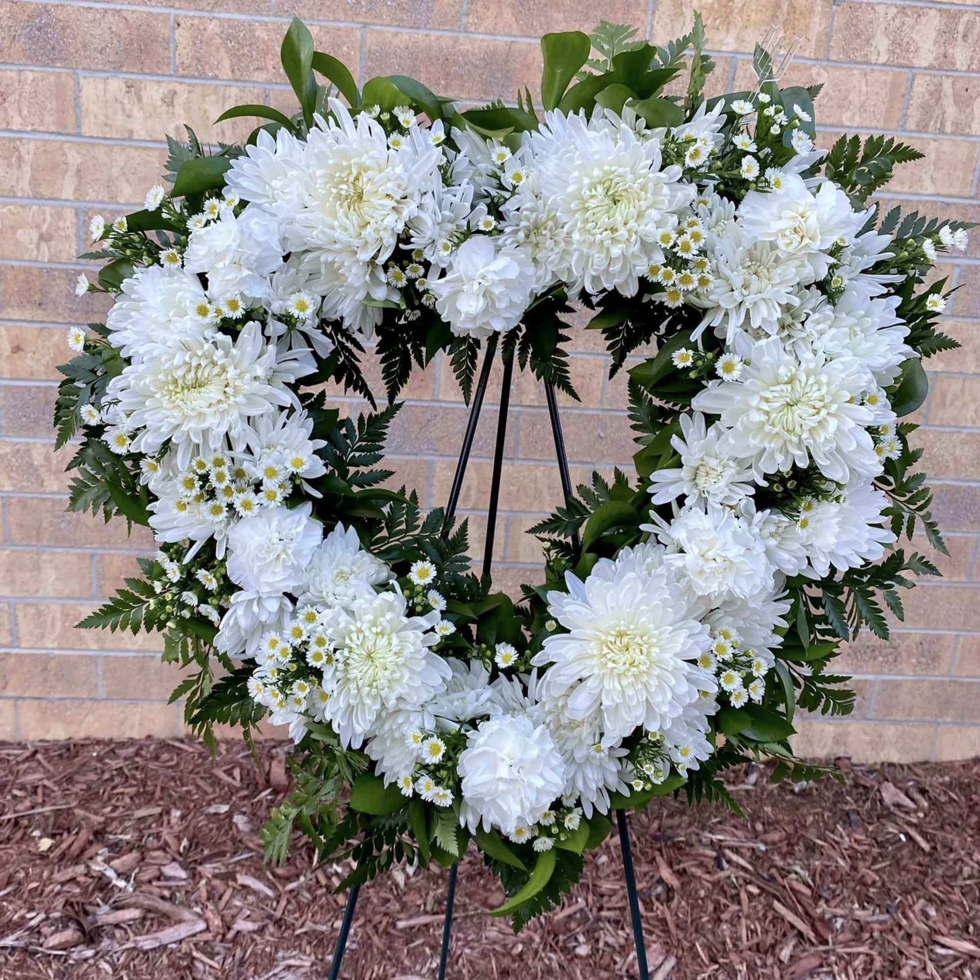 Heart-shaped white chrysanthemum and daisy standing wreath on a metal easel