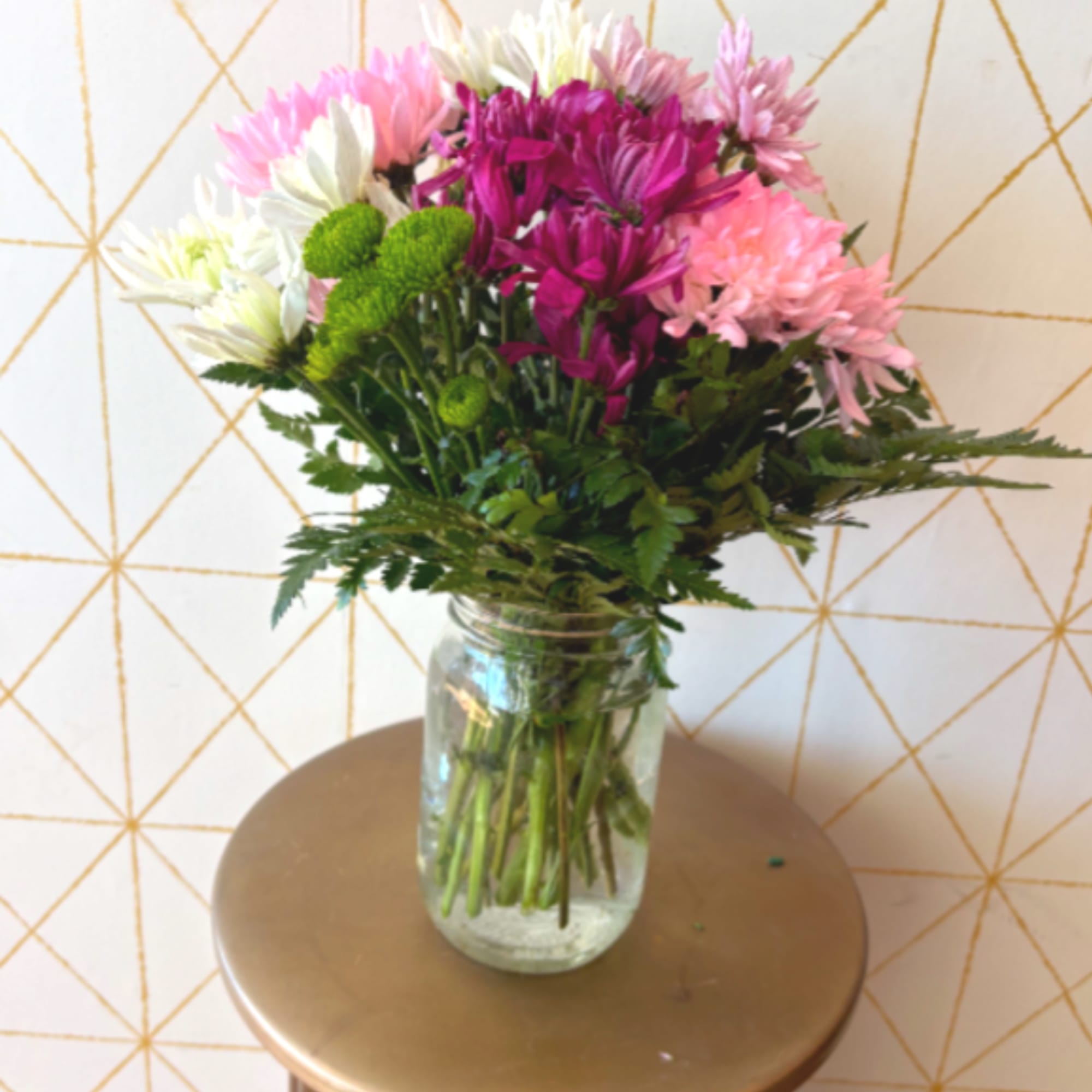 Bouquet of pink, white, and purple flowers in a glass jar vase