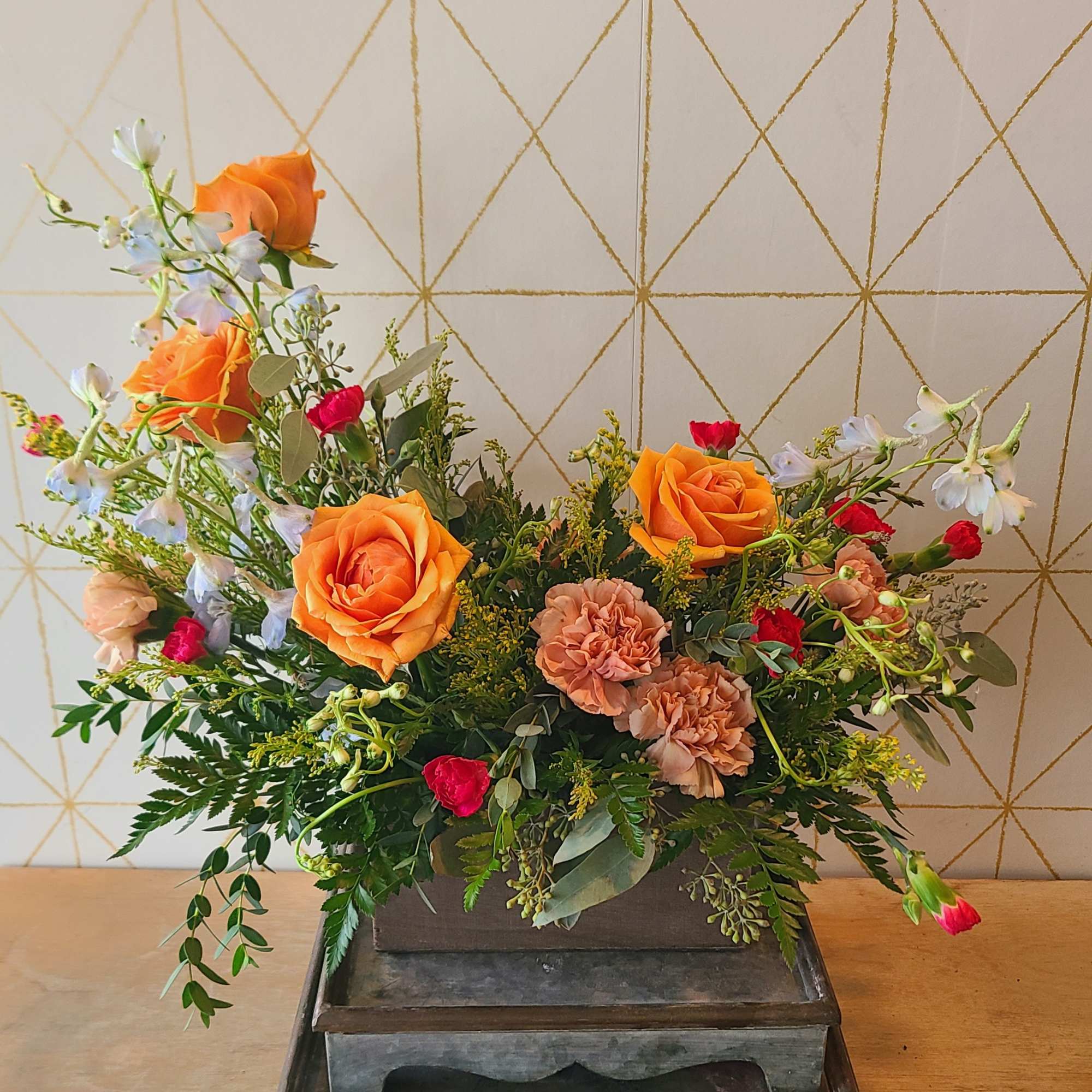 Orange roses and peach carnations in a rectangular wooden container