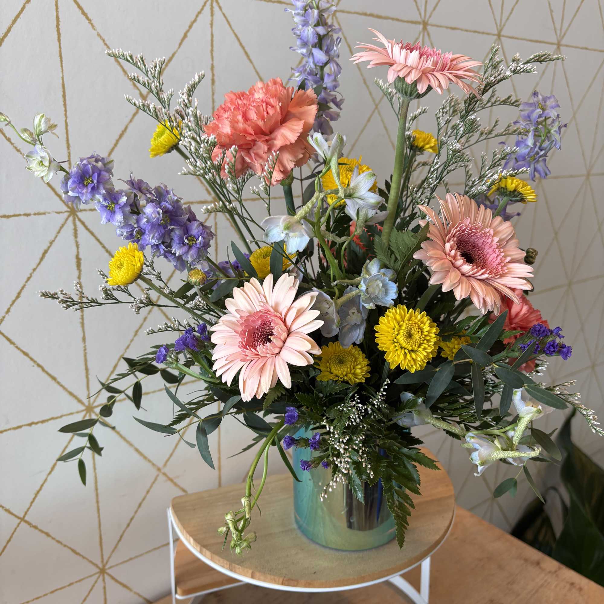 Mixed bouquet with pink gerbera daisies and purple flowers in a glass vase