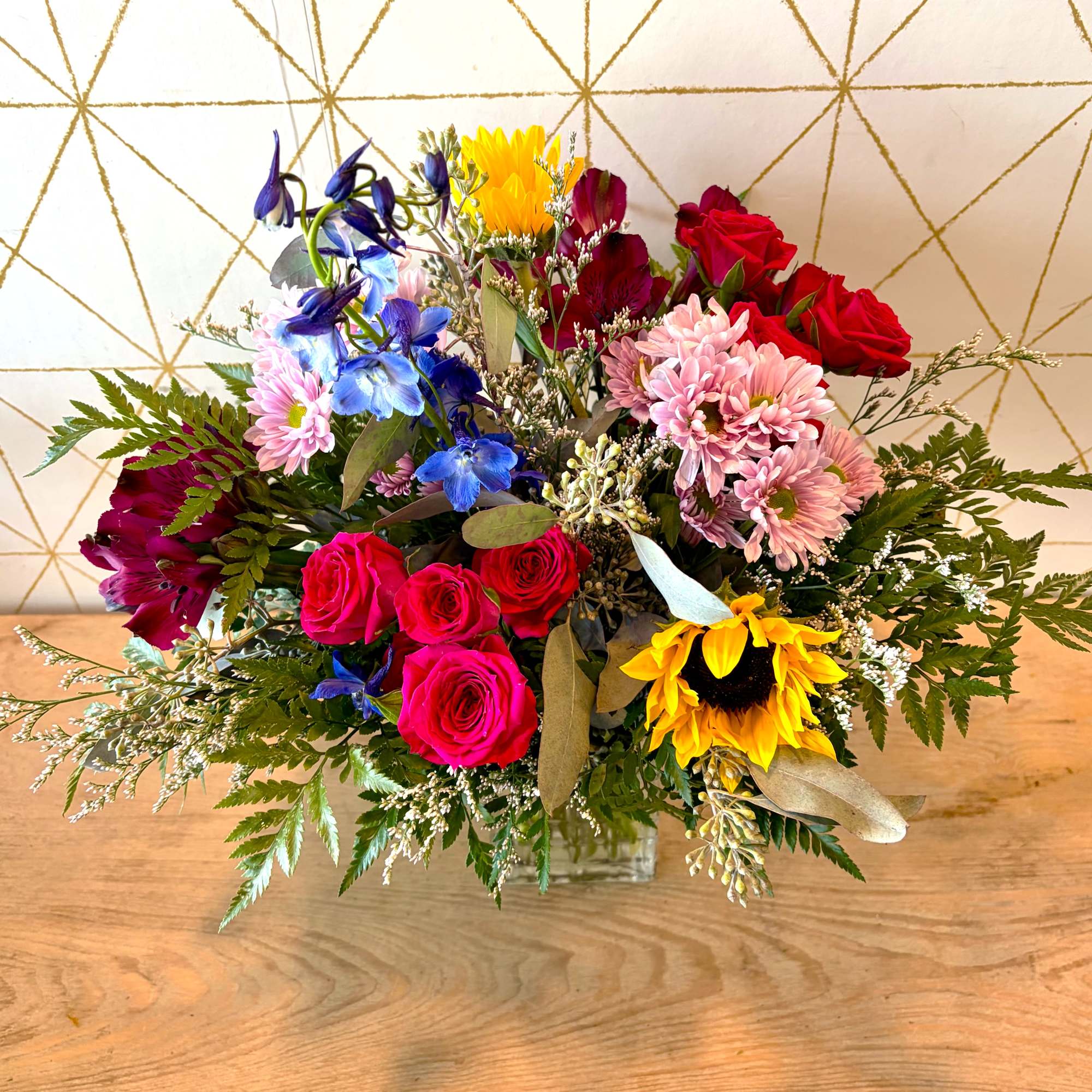Mixed bouquet with roses, sunflowers, and blue flowers in a glass vase, photo 2 of 4