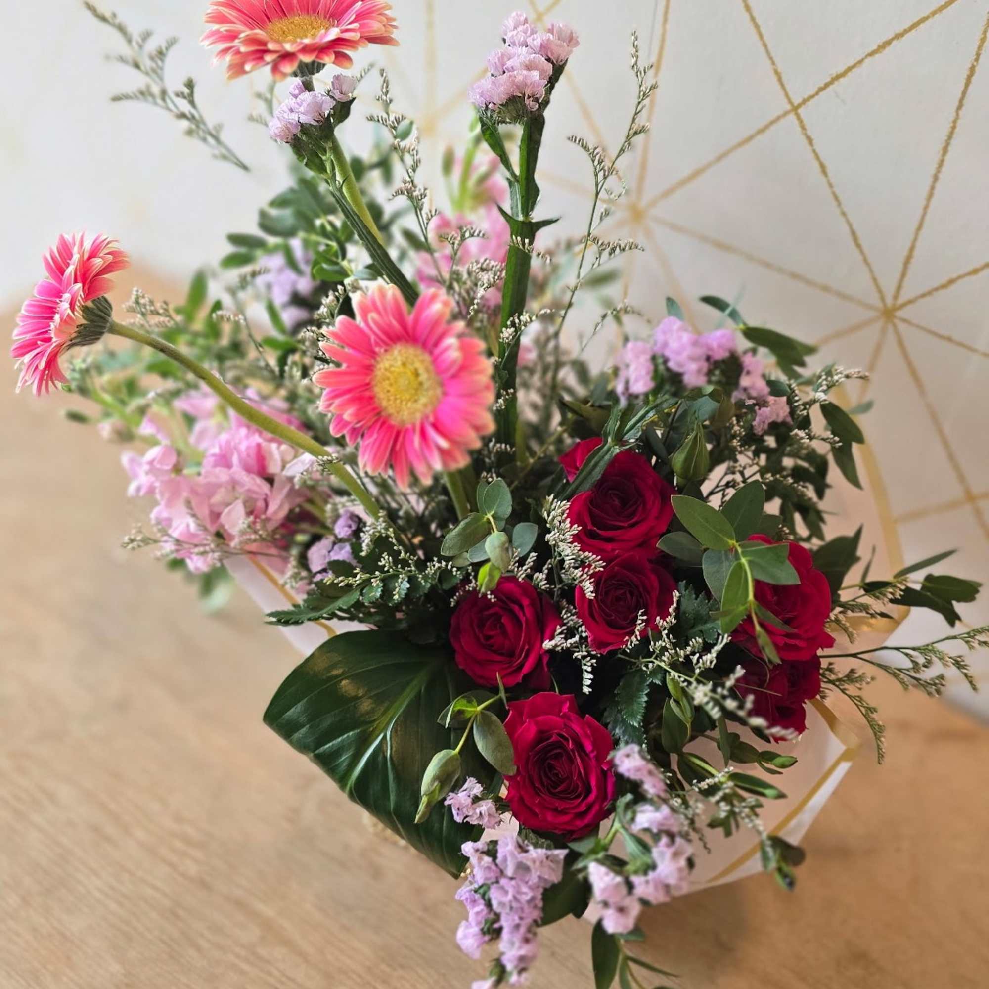 Bouquet of pink gerbera daisies and red roses with small lavender filler flowers
